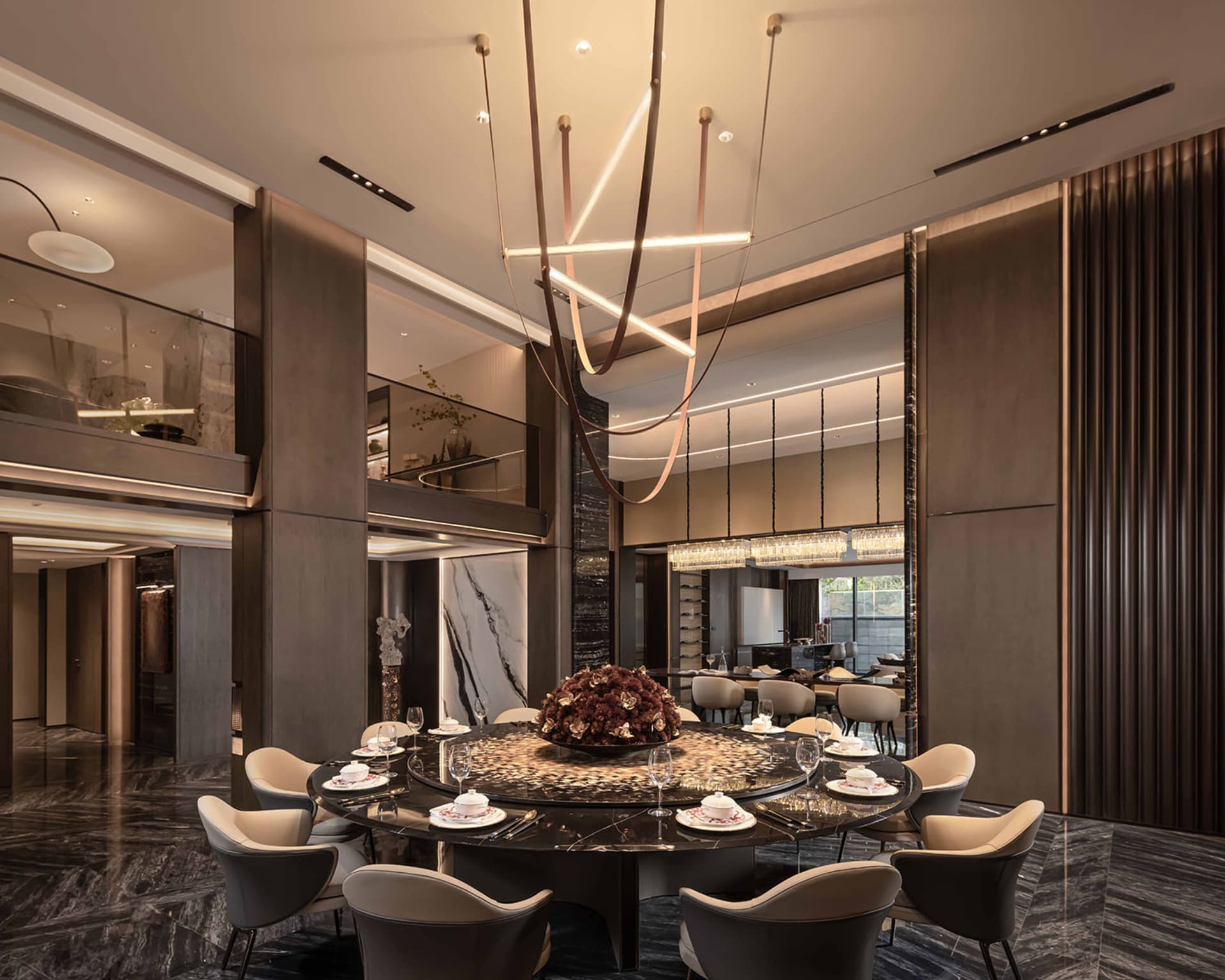 A modern dining room with a round table, chairs, wine glasses, and vases, lit by a chandelier and natural light