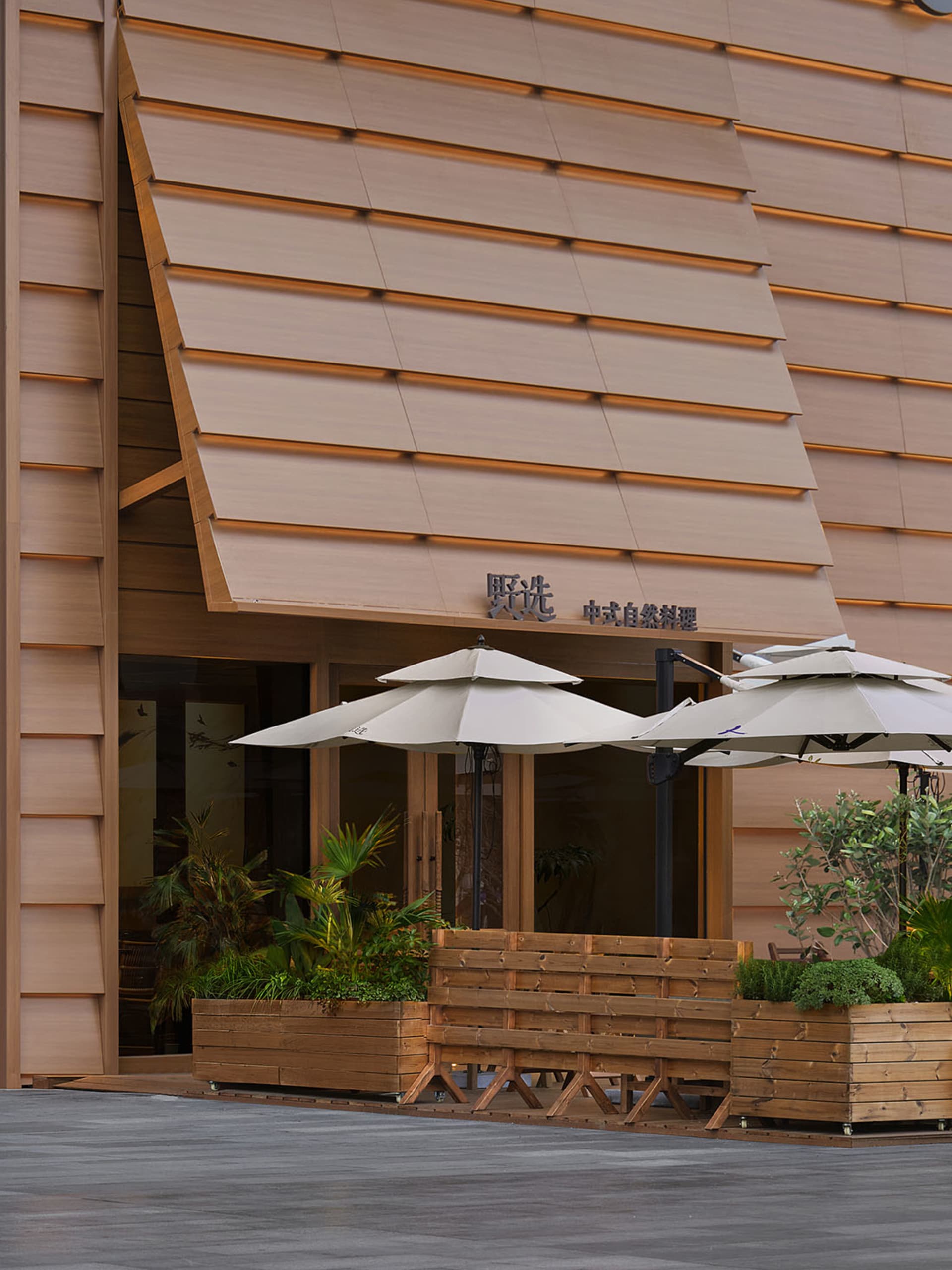 Photograph of a traditional building with a brown wooden exterior, featuring a large wooden awning and a wooden bench in front of it