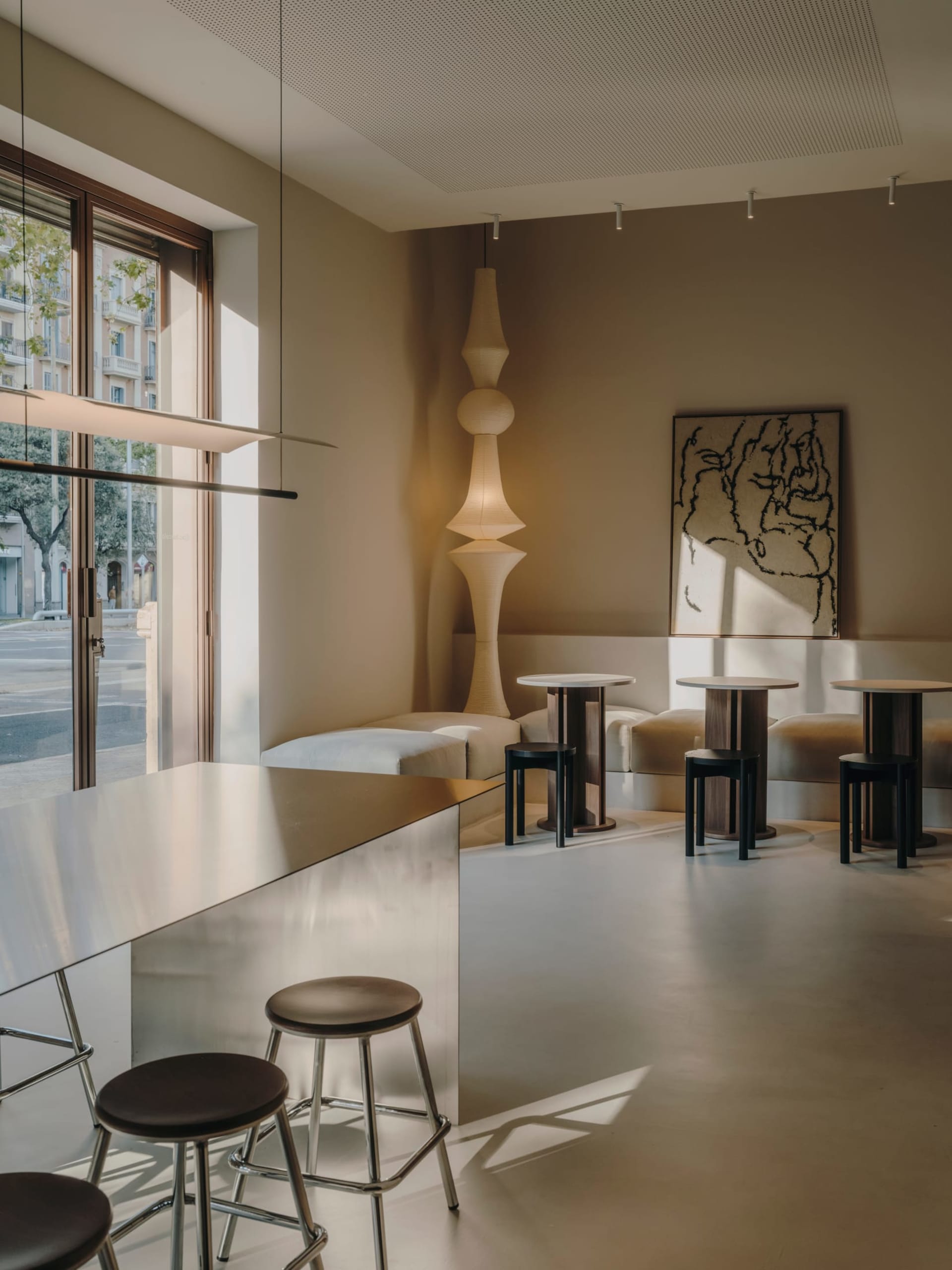 Well-lit contemporary bar with a counter, stools, and decorative items, set in a restaurant or bar space with soft and warm lighting