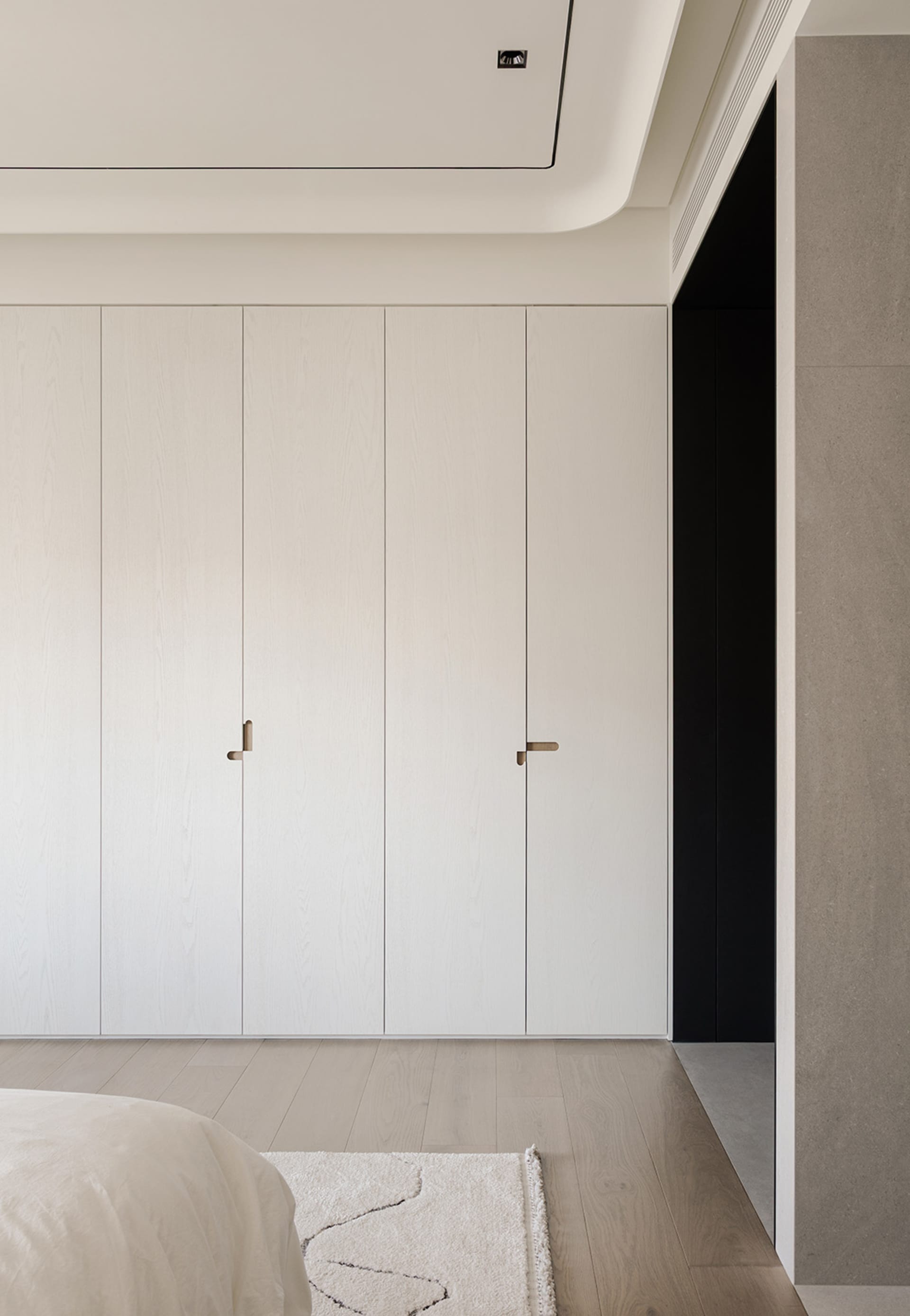 A cozy bedroom with a large wooden cabinet and a bed, featuring a warm and natural design
