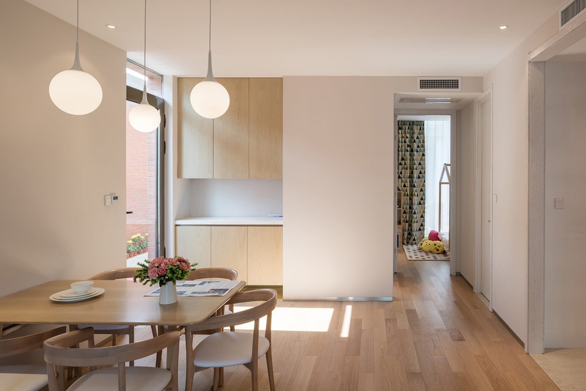 A modern kitchen and dining area with a wooden table, chairs, and cabinets, surrounded by a cozy atmosphere and natural light