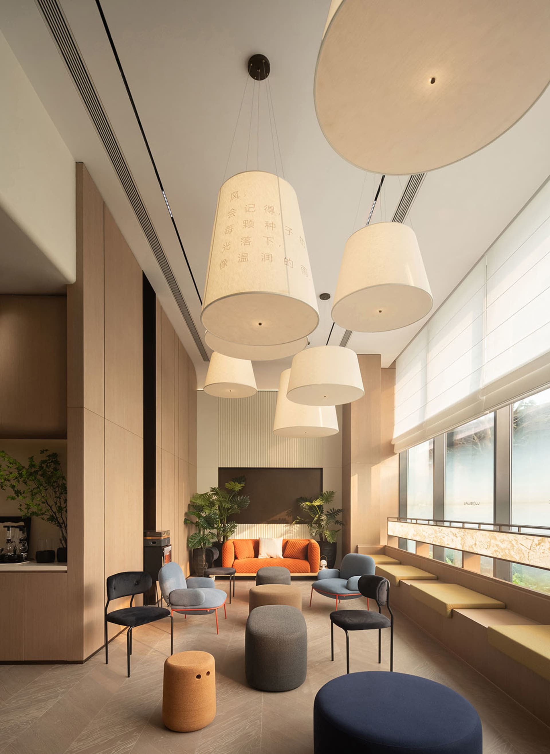 A well-lit modern living room with a wooden floor, chairs, and a couch, featuring a large window for natural light and a warm atmosphere
