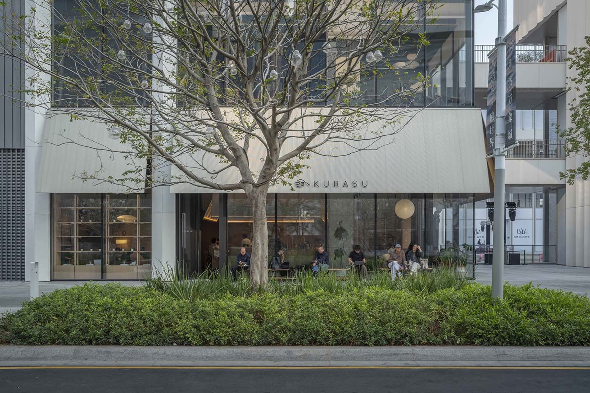 A lively restaurant interior with a tree in the center, surrounded by people, chairs, and dining tables