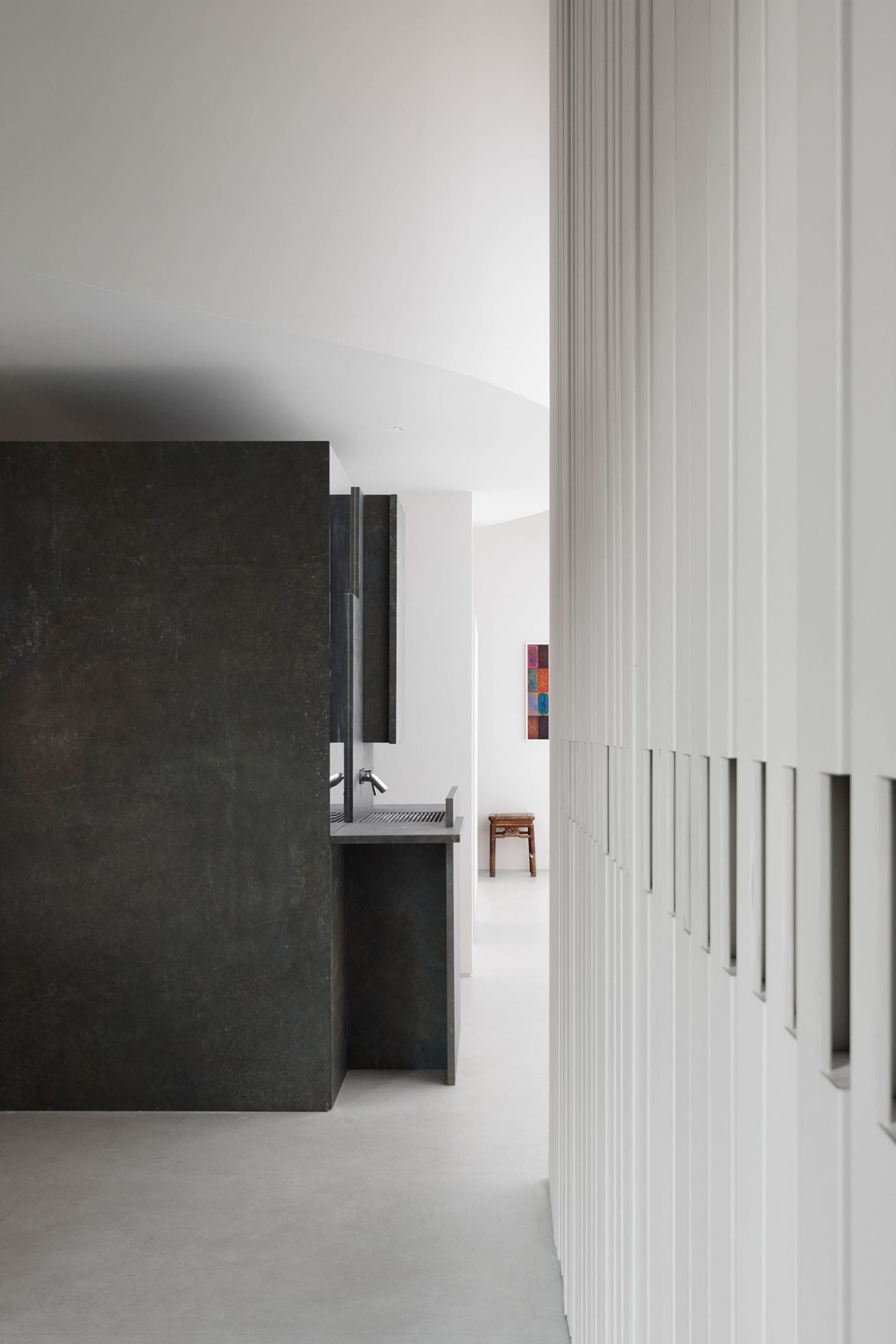 Modern kitchen with a black granite countertop, black cabinets, a sink, and refrigerator in a dimly lit space