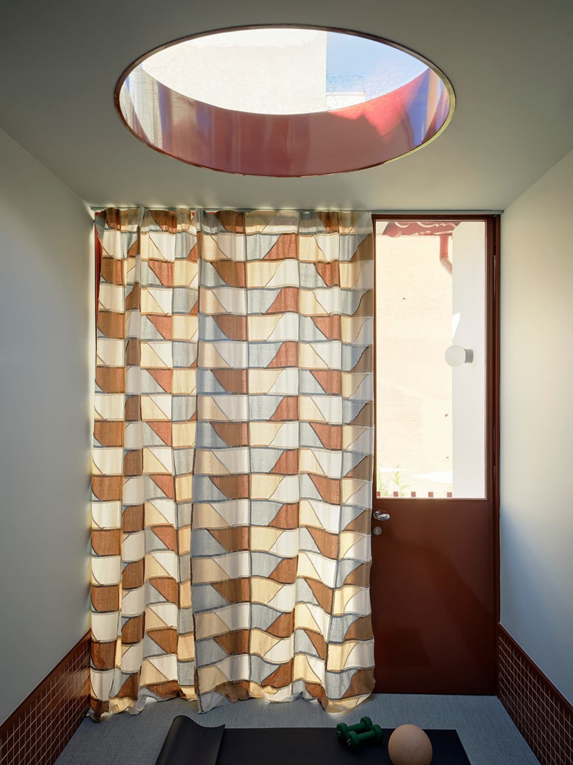 A dimly lit bedroom with a bed in the background and a brown curtain with a patterned design covering the doorway