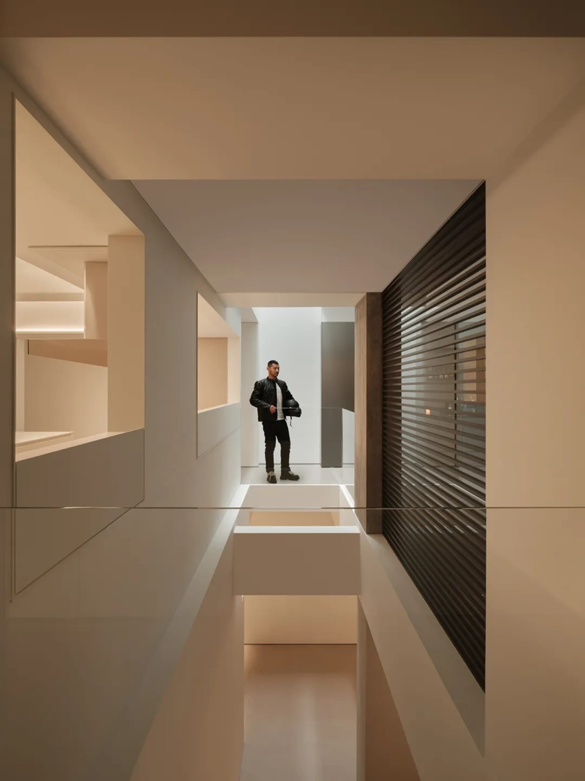 A man stands in a modern room with a white wall, glass wall, and black and white color scheme, creating a calm and serene atmosphere