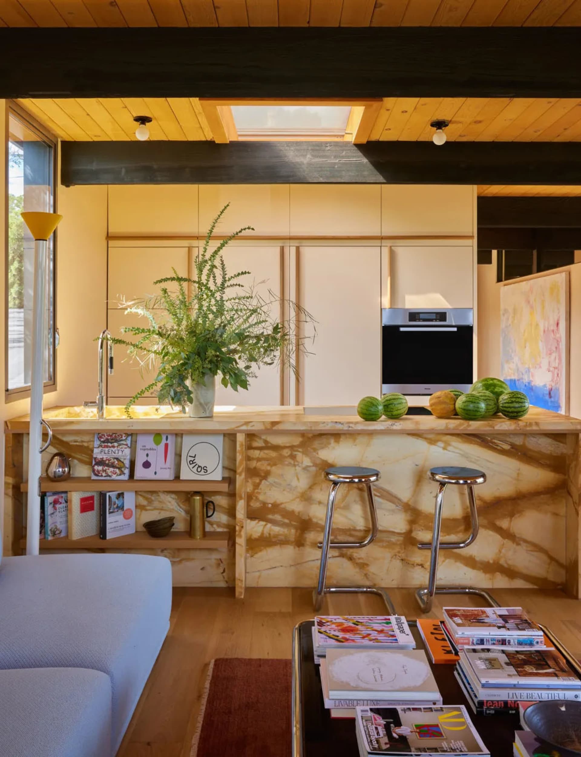 Warm and inviting kitchen with a marble counter, wooden floor, and well-lit space with stools and a microwave