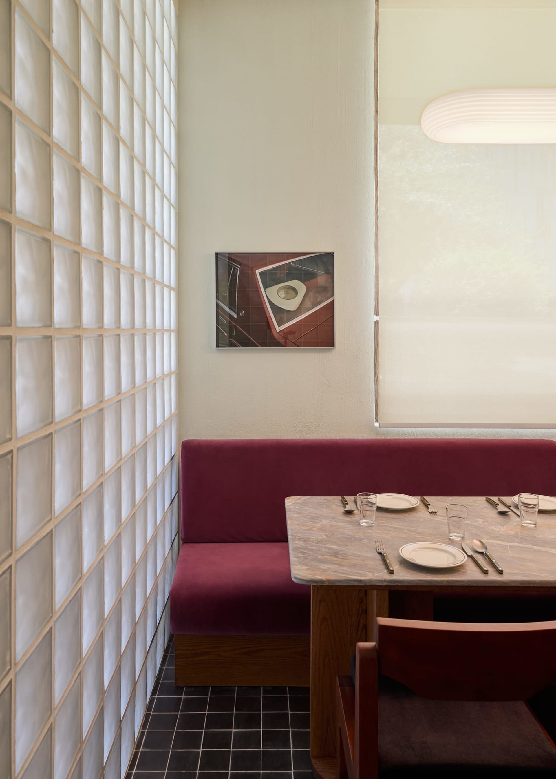 A well-lit dining room with a purple couch, a dining table set with tableware, and a painting above the table