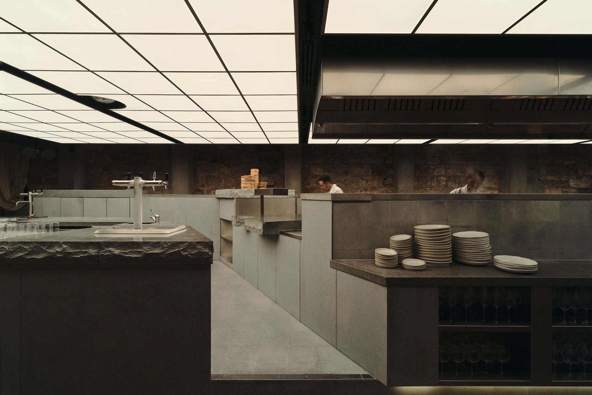 A modern kitchen with a gray color scheme, featuring marble countertops, stainless steel appliances, and a cozy atmosphere with dim lighting