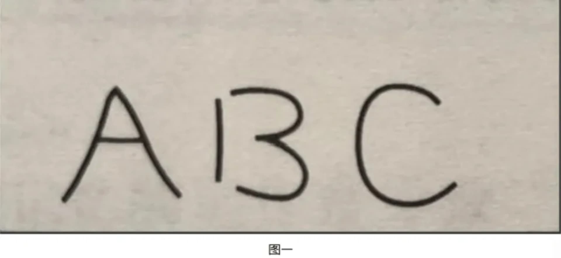 A dimly lit room with a white wall and a black letter A on it, with a bed in the background