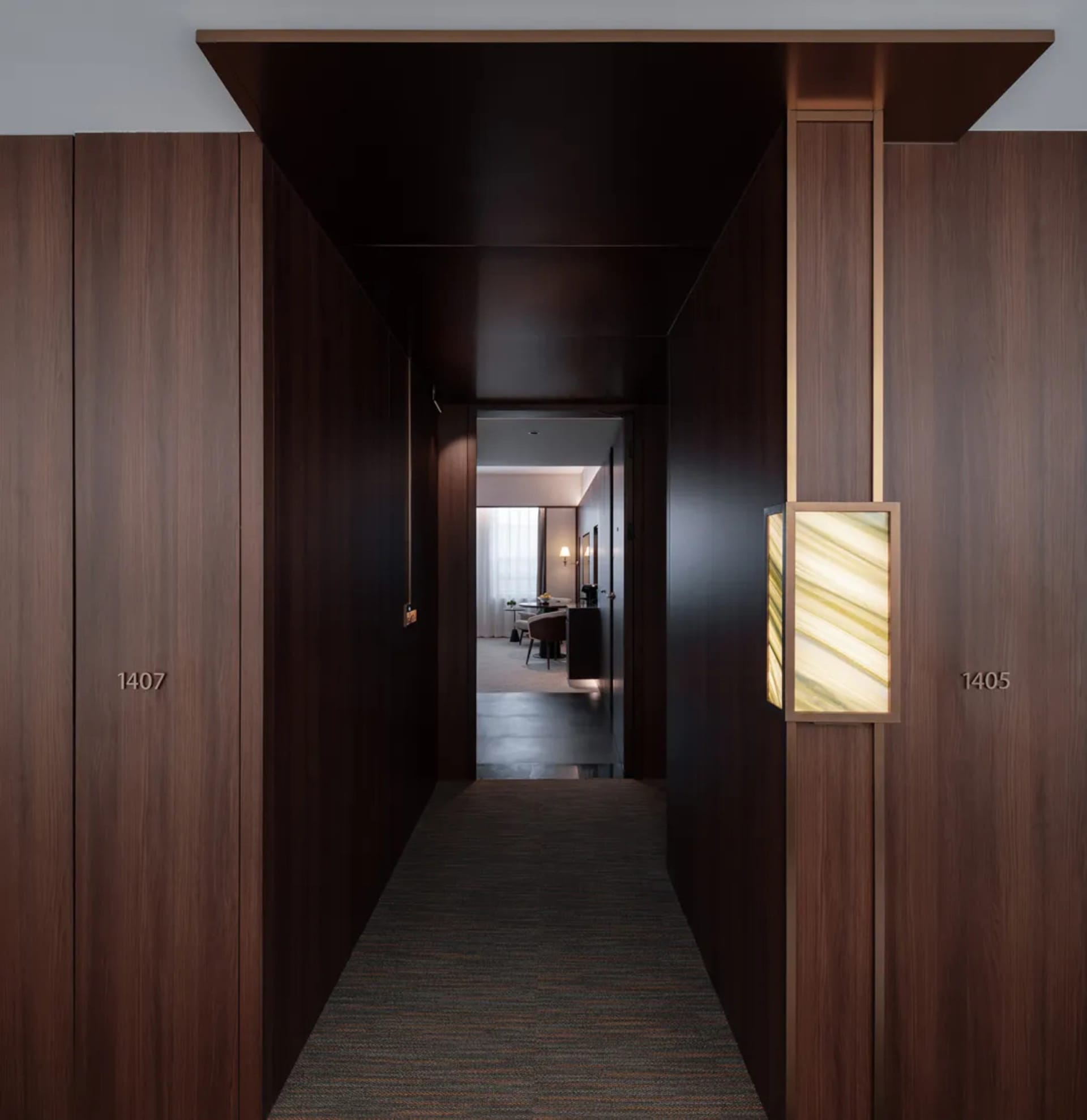 Dark hallway with a wooden surface, carpeted floor, and a doorway at the end