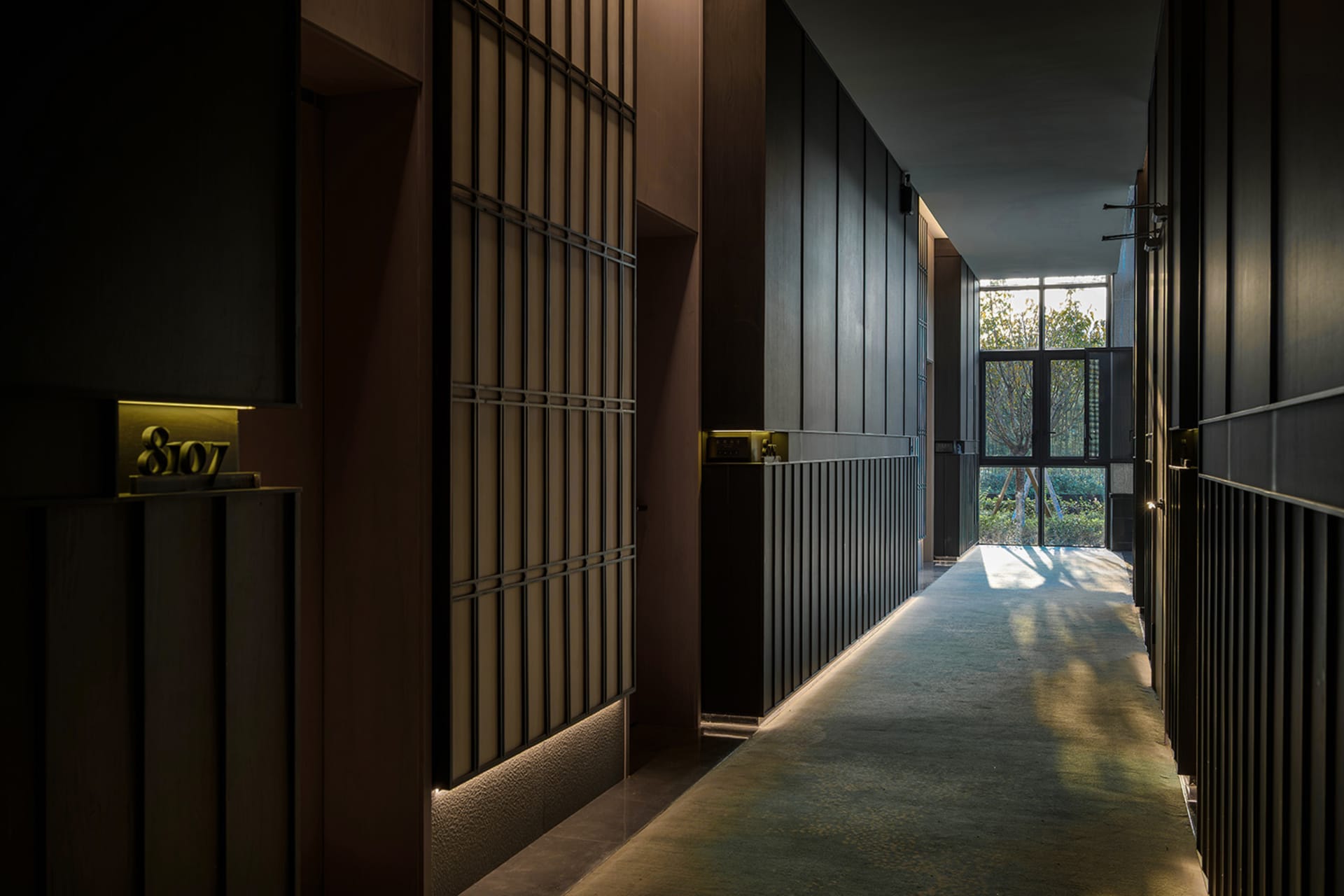 A dimly lit, modern hallway with wooden paneling and a carpeted floor, creating a cozy atmosphere