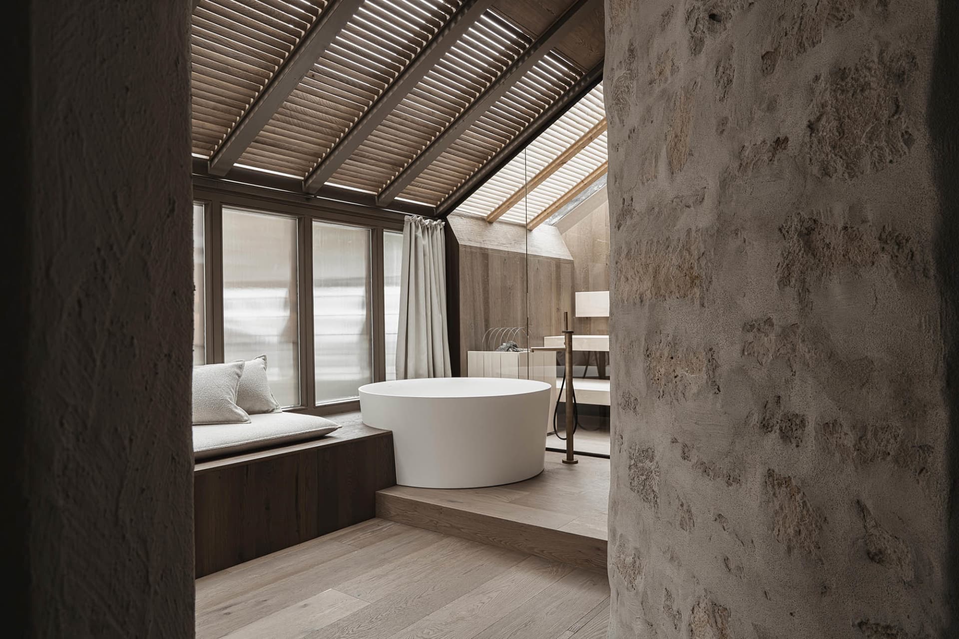 Dimly lit bathroom with a white bathtub, wooden accents, and a sink to the right of the bathtub