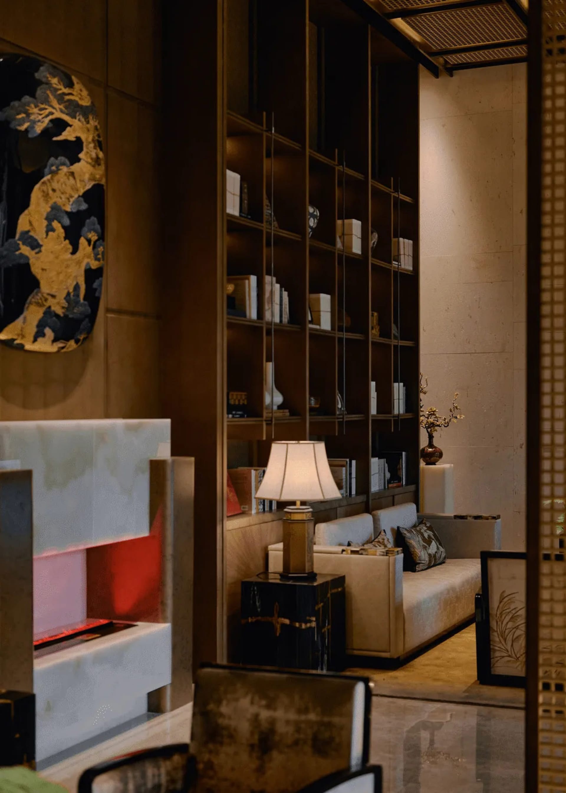 Cozy modern living room with a couch, chair, lamp, bookshelf, and fireplace, decorated with books and warm dim lighting