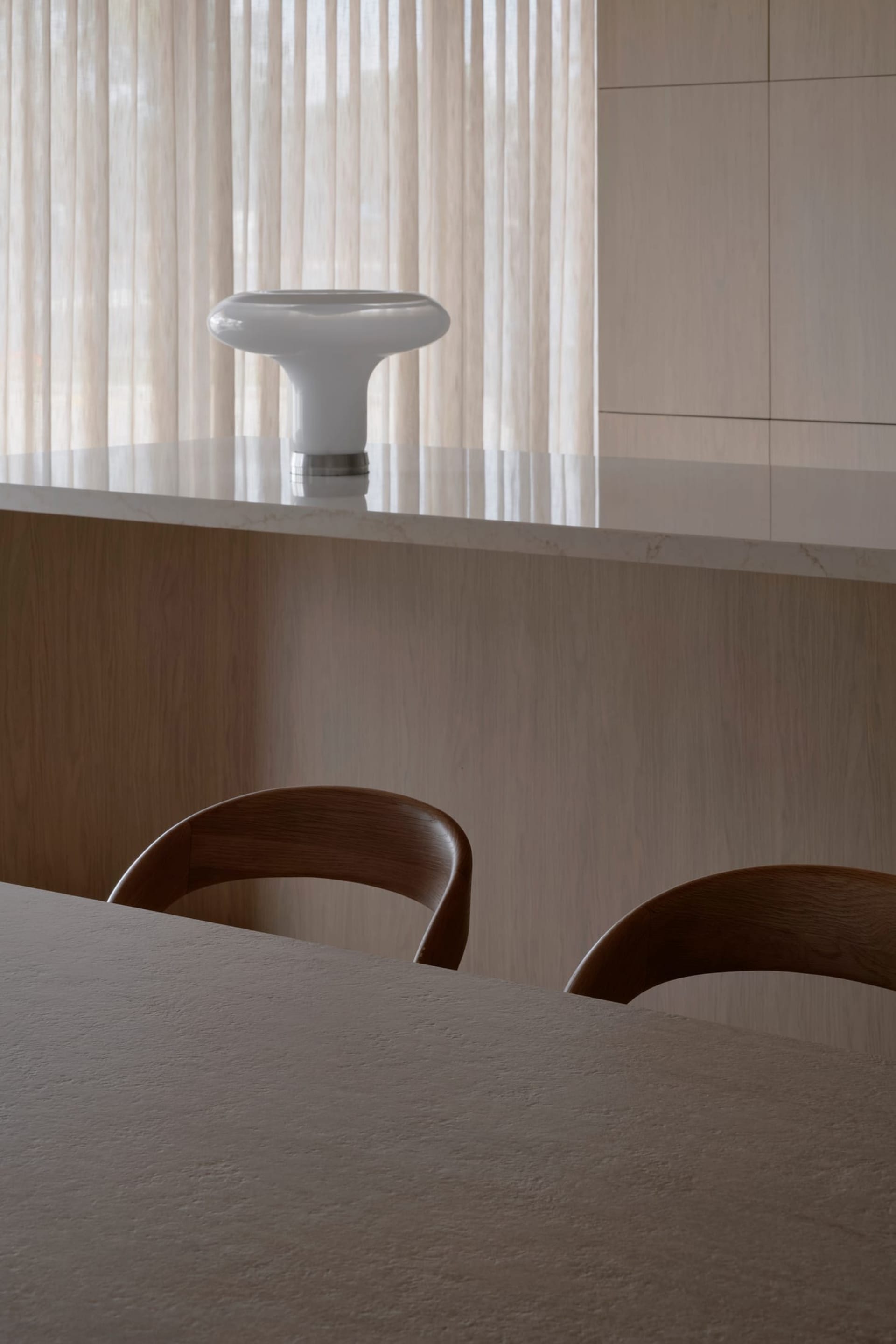Cozy kitchen with wooden floors, a wooden table, and chairs, featuring a sink, counter, and window in a dimly lit space