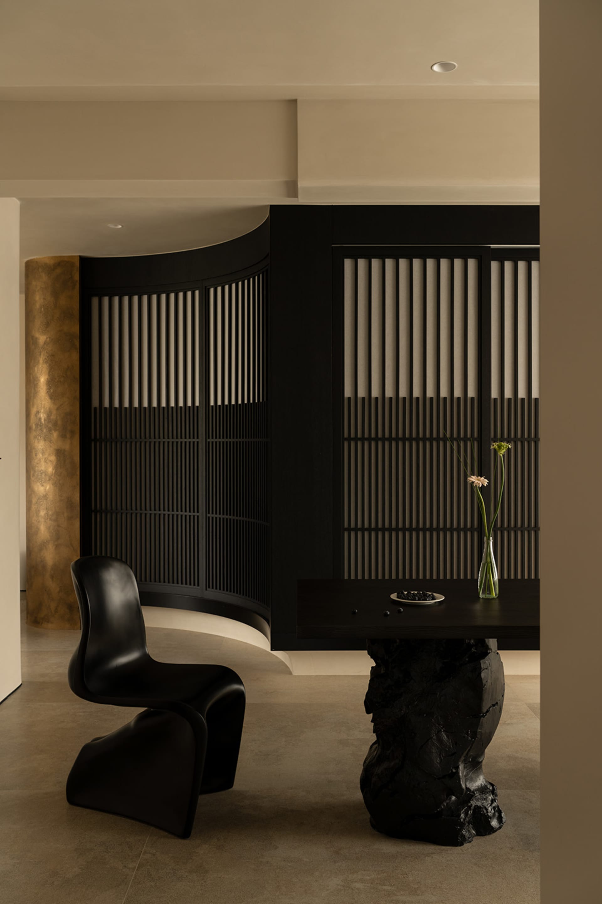 A modern living space with a black chair, dining table, and vase with a flower, set against a black and white color scheme