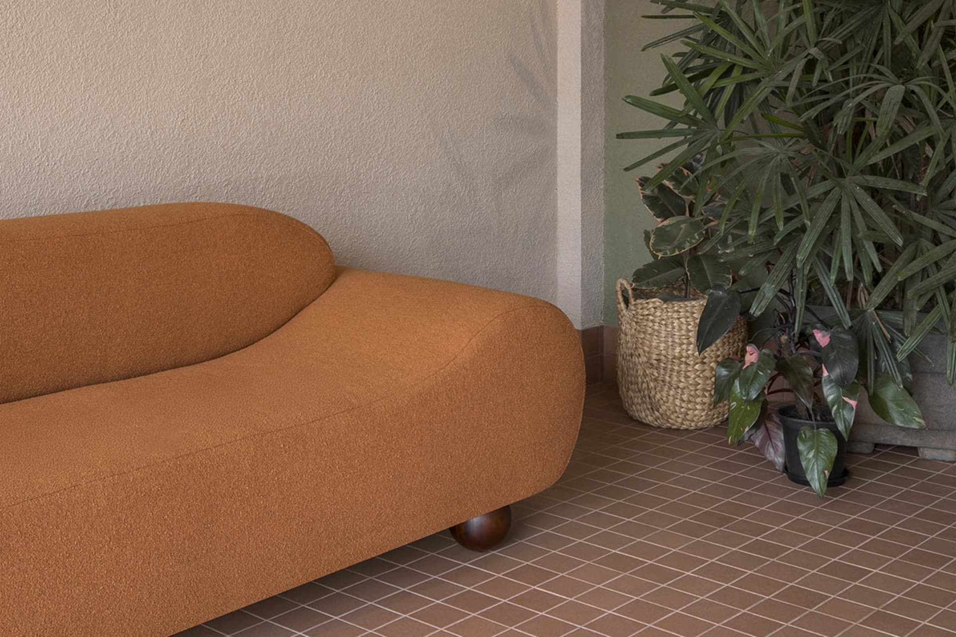 A well-lit living room with a brown couch and a potted plant, creating a comfortable and inviting atmosphere
