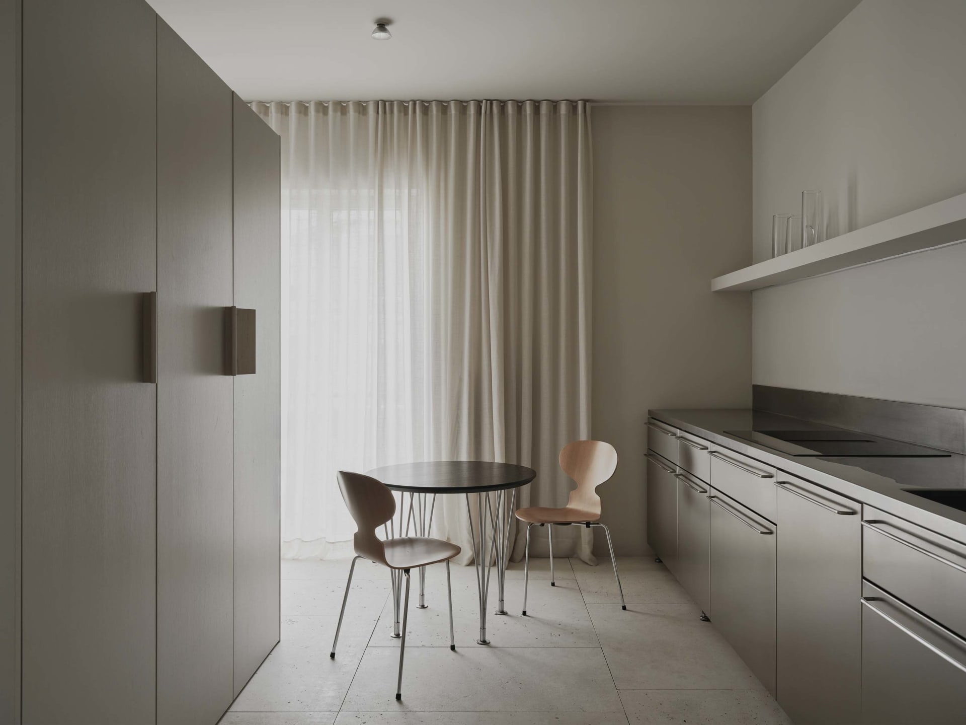 A well-lit modern kitchen and dining area with a wooden table and chairs, a sink, refrigerator, and window