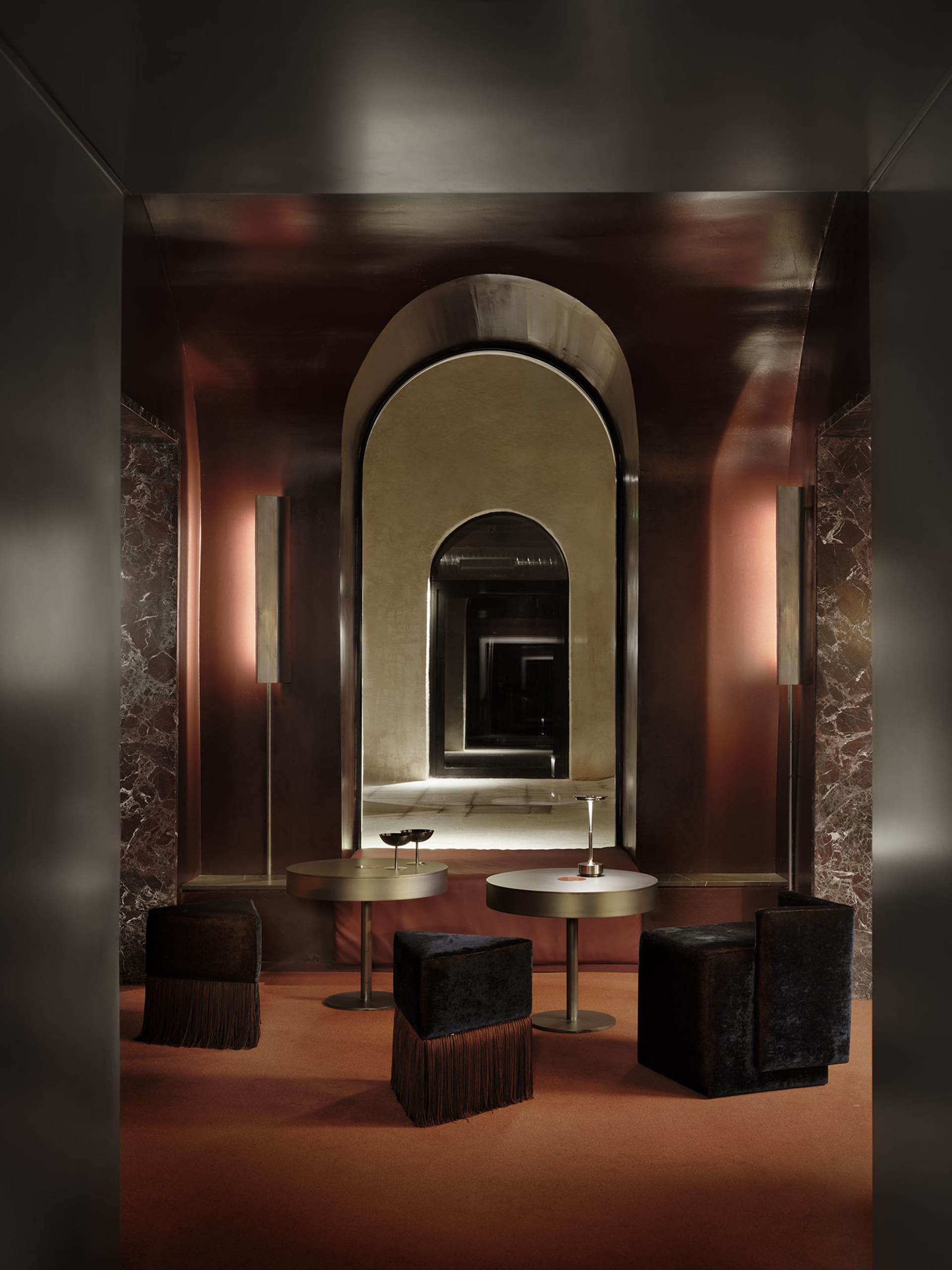 A modern living dining area with a brown color scheme, featuring a large arched doorway, a mirror, and a table with chairs, surrounded by a well-lit space with natural light