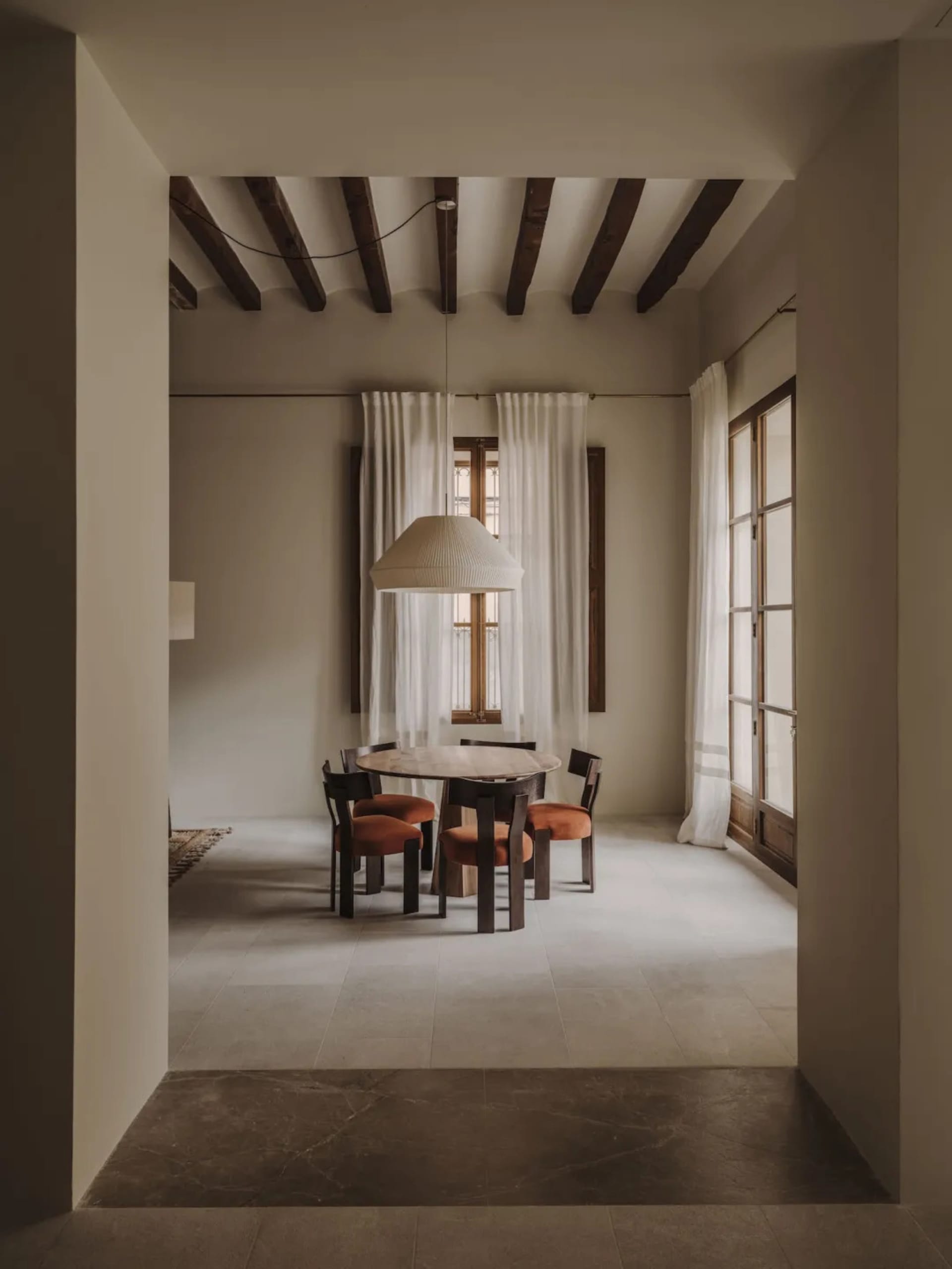 A dimly lit dining room with a wooden table and chairs, surrounded by other furniture, creating a cozy atmosphere