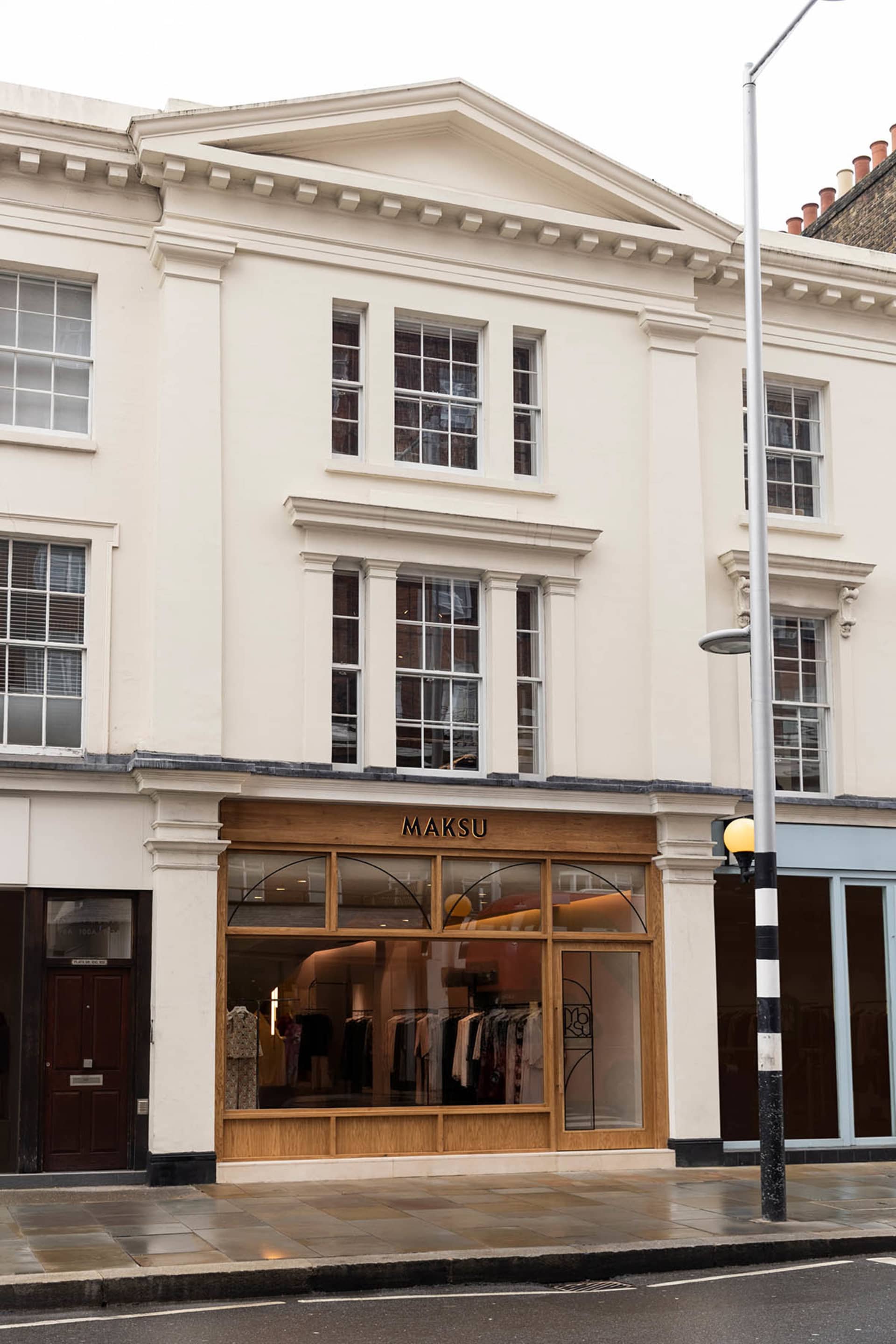 A classical building with a wooden storefront, brick facade, and elegant interior with mannequins on display
