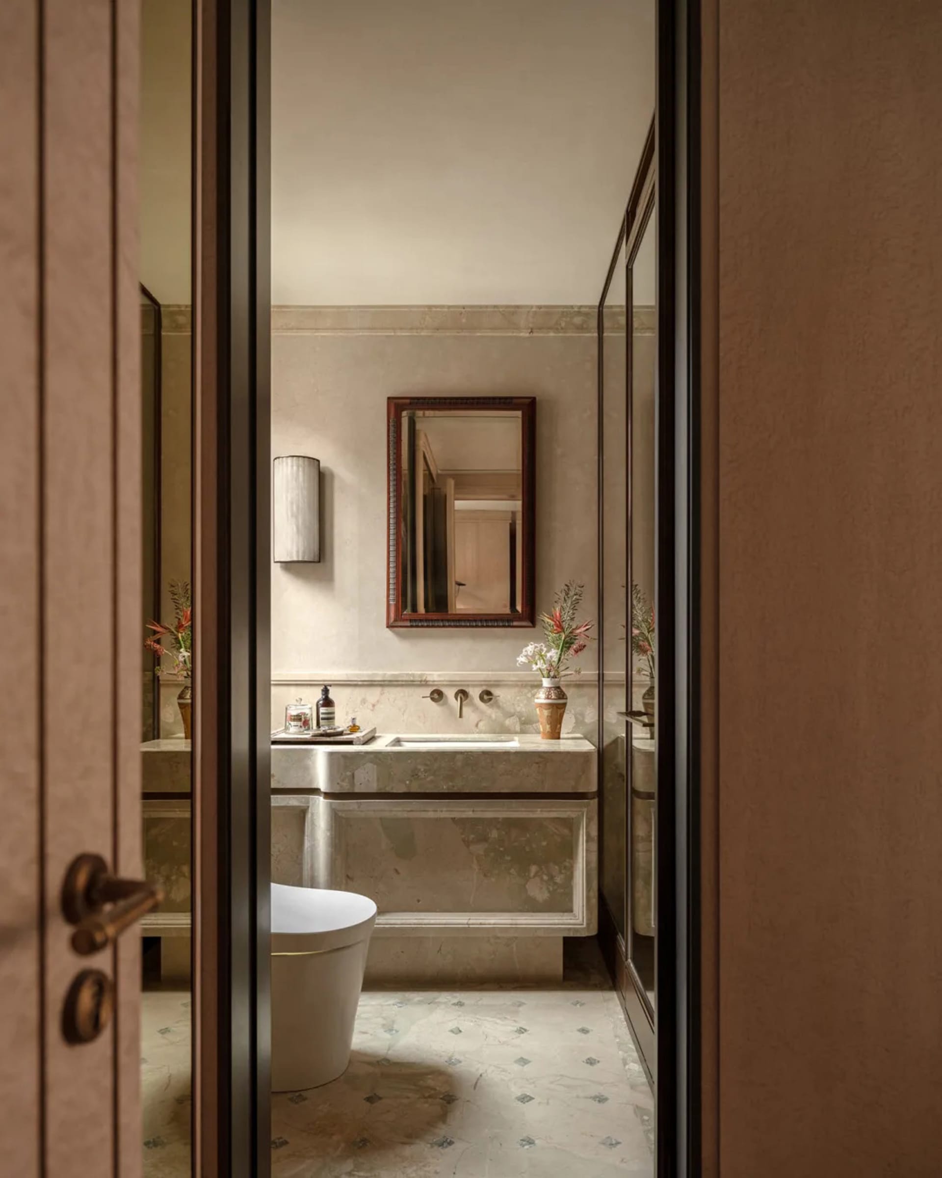 A dimly lit bathroom with a white toilet, sink, and bathtub, set against a residential background with a brown door