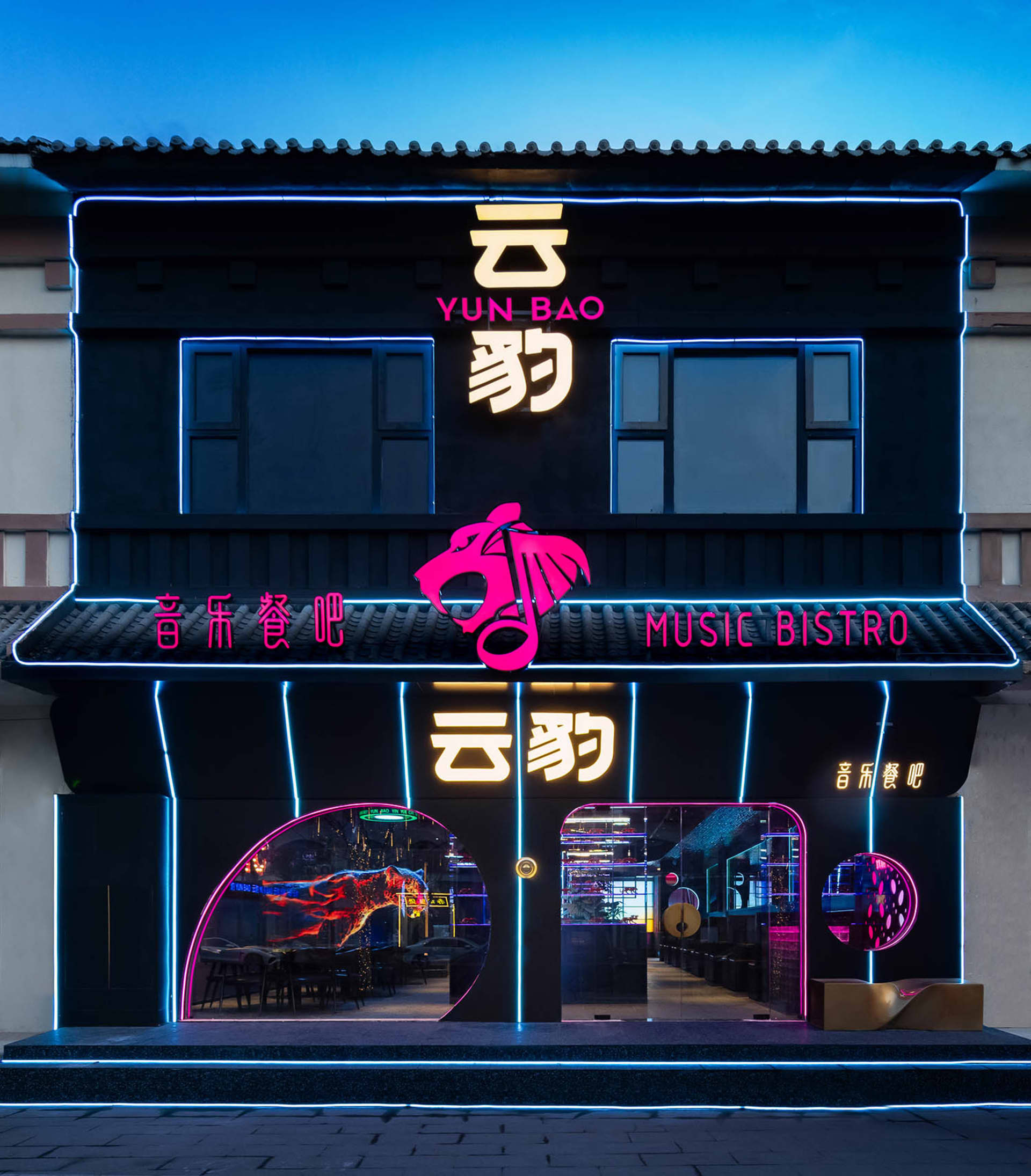 一座黑色的建築物，擁有外用外語的霓虹燈招牌，創造出活躍且吸引人的氛圍