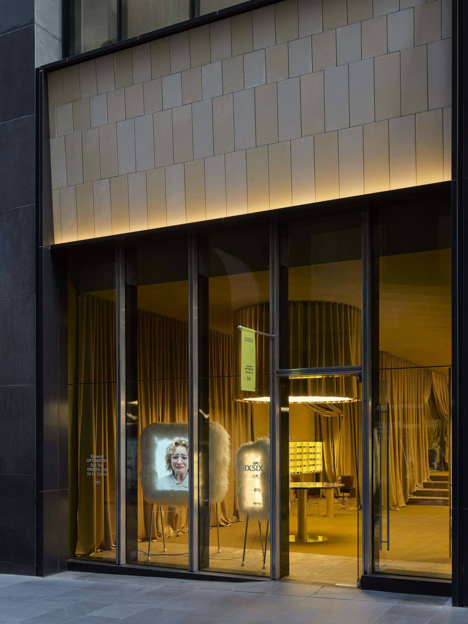 A retail store with a glass door and a display of a woman's face on a screen, creating a modern and stylish atmosphere