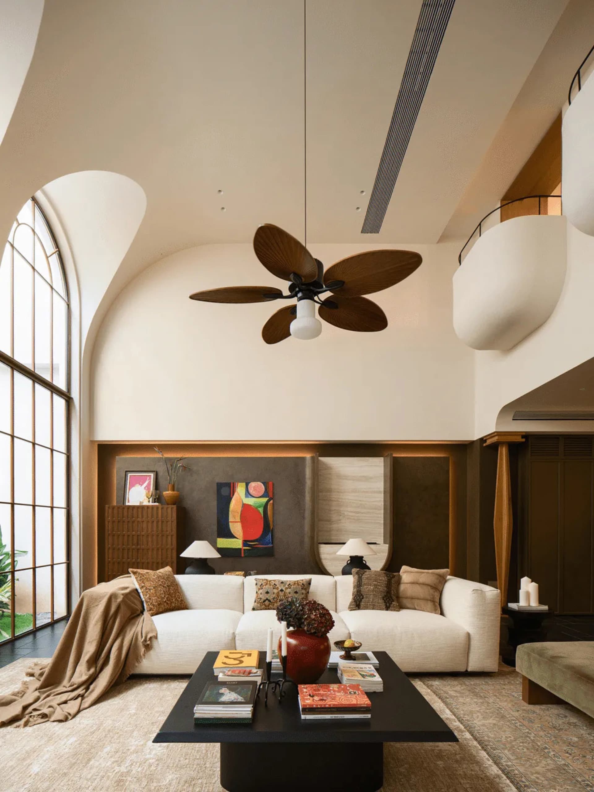 A well-lit living room with a white couch, coffee table, and ceiling fan, creating a comfortable and inviting atmosphere