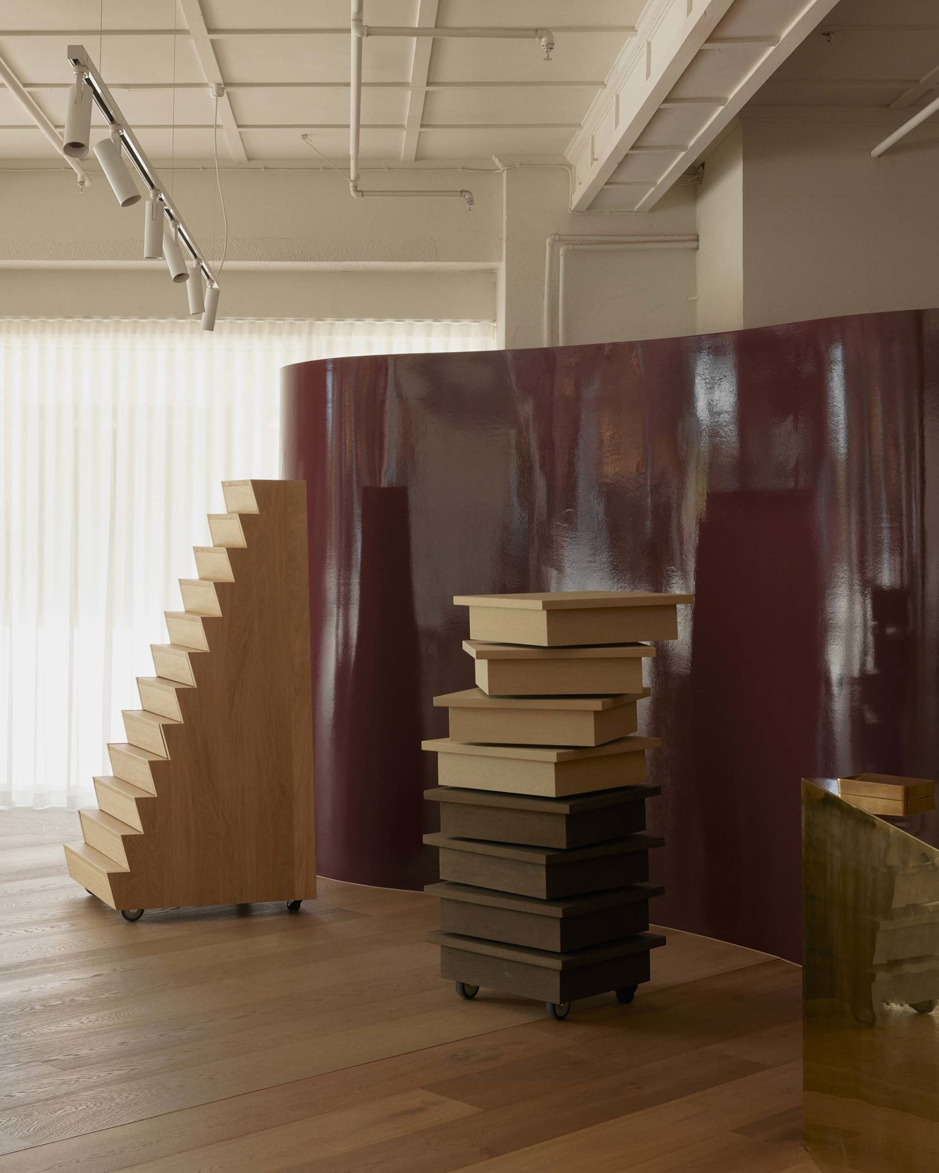 Cozy study with a purple accent wall, wooden floor, and a large bookshelf with various books, natural light from a window