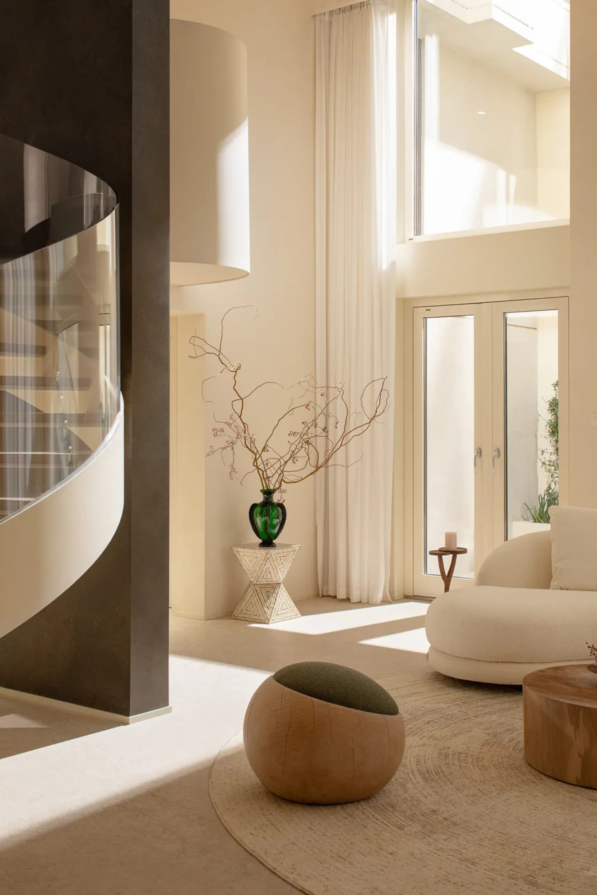 A modern living room with a white couch, chair, and dining table, decorated with a vase and potted plant, in a well-lit space with a contemporary style