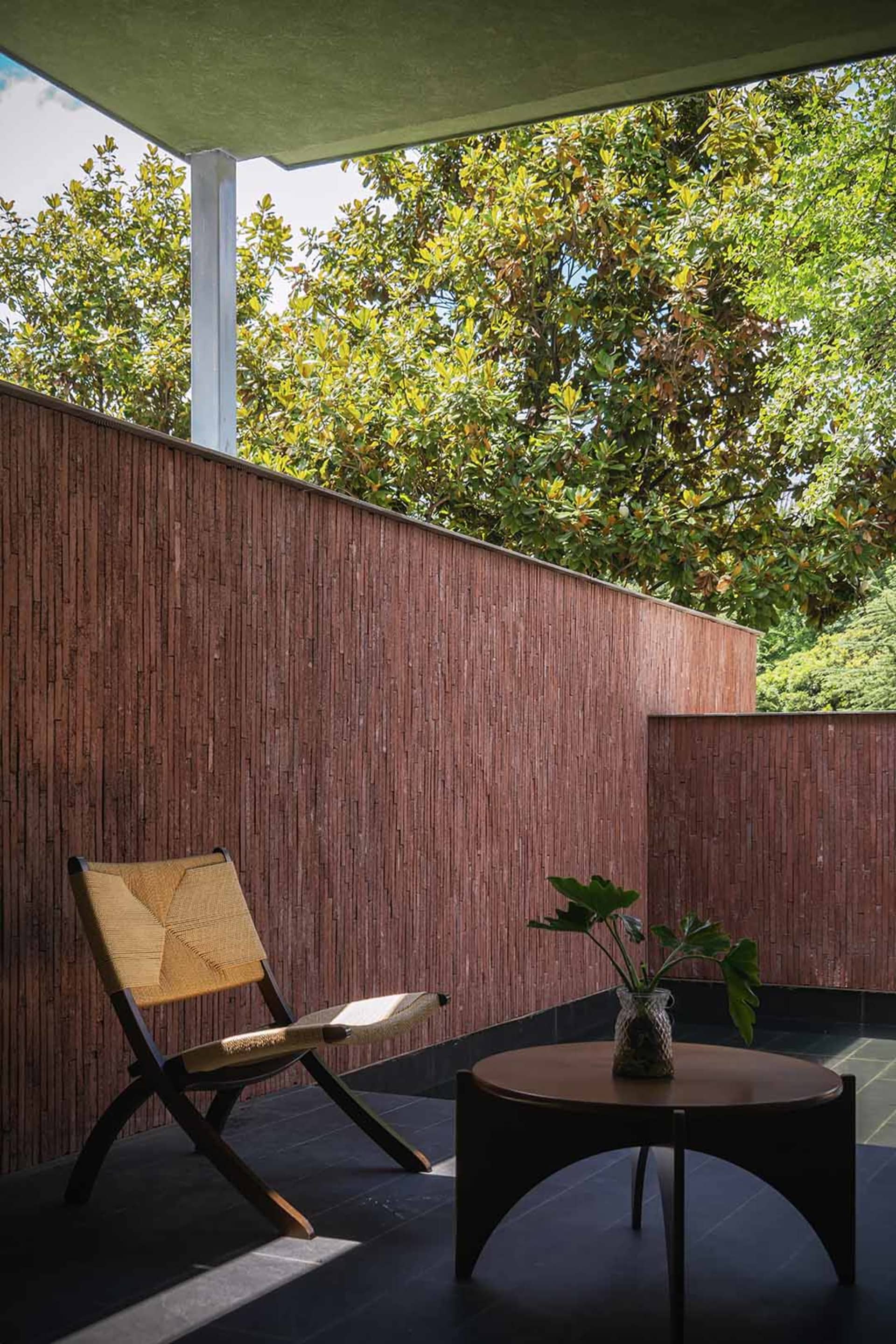 Warm living space with a brown wall, red wall, wooden floor, chair, potted plant, and dining table