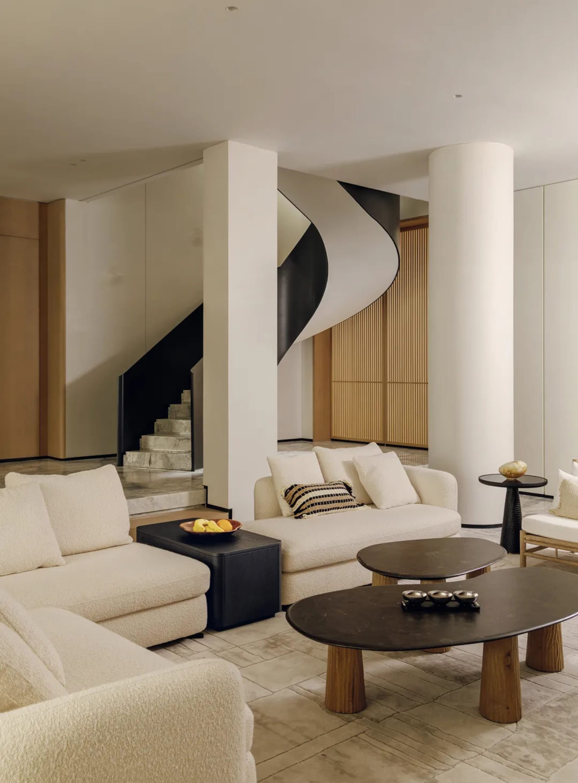 A modern living room with white furniture, decorative items, and a bright atmosphere, featuring a couch, chair, dining table, and potted plant