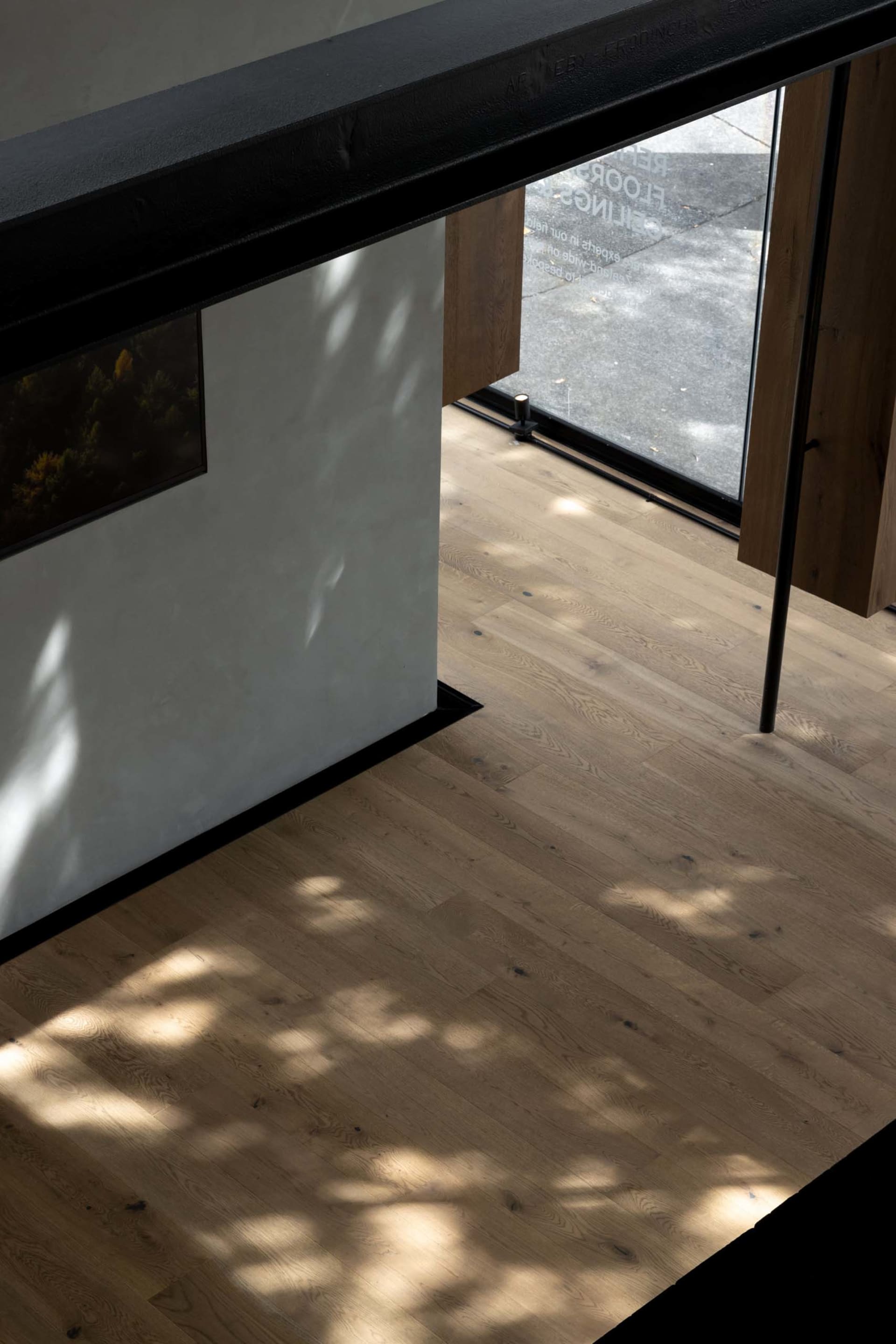Bright and inviting kitchen with wooden floors, a white wall, a sink, a refrigerator, and natural light from a window