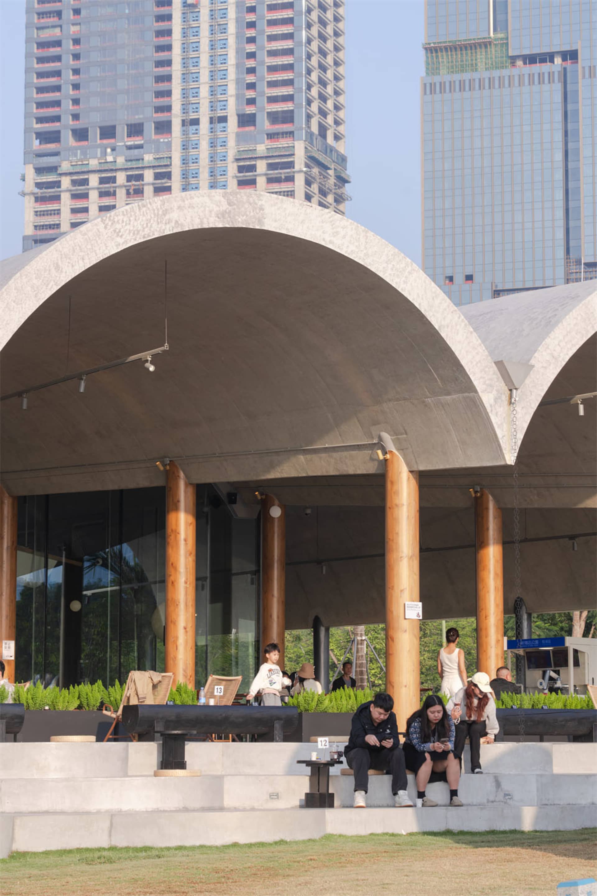 Large commercial space with high ceiling, concrete and wood elements, natural light, and modern design