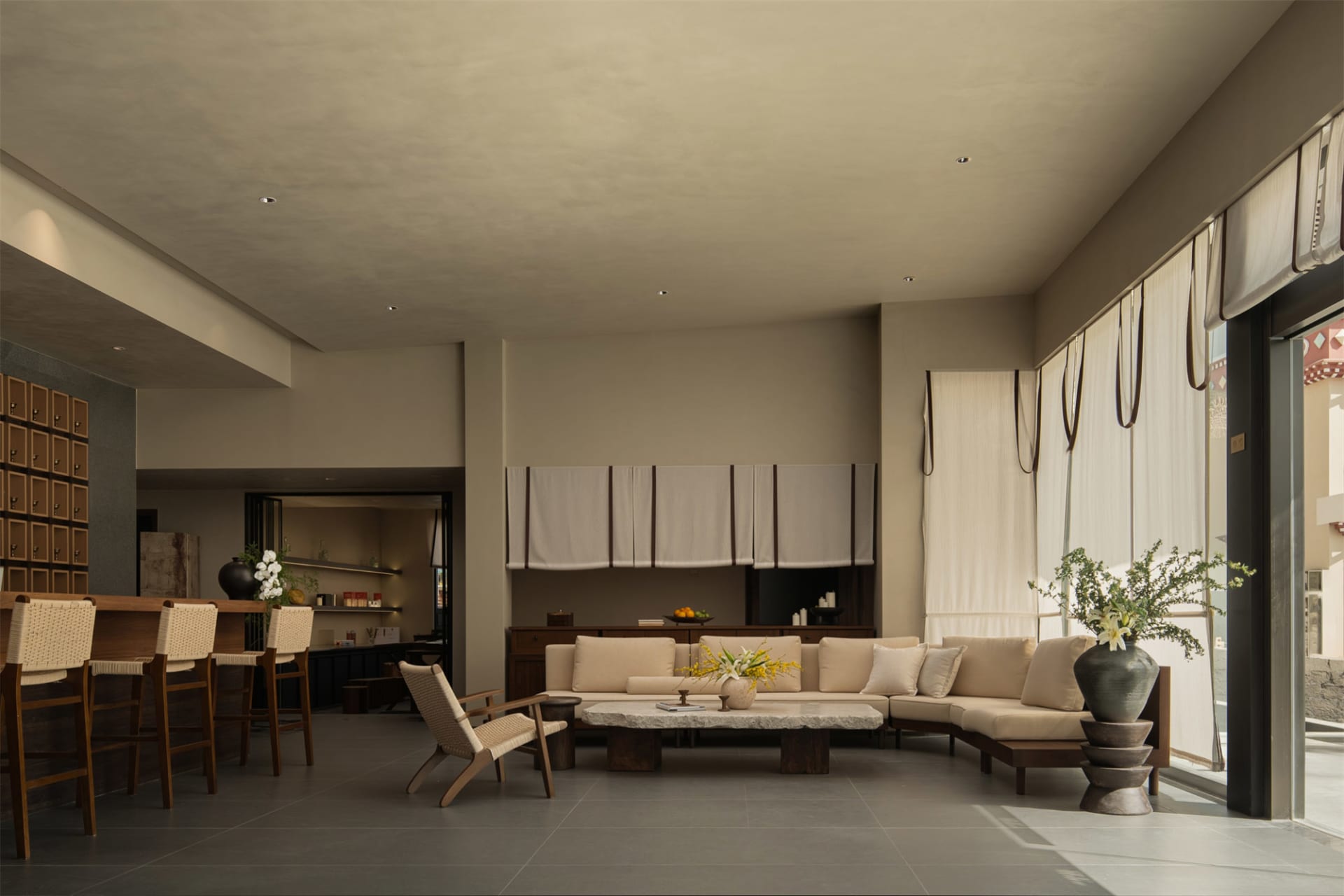 Comfortable and inviting living space with a large couch, chair, dining table, and decorative elements, featuring a large window with natural light and soft warm lighting