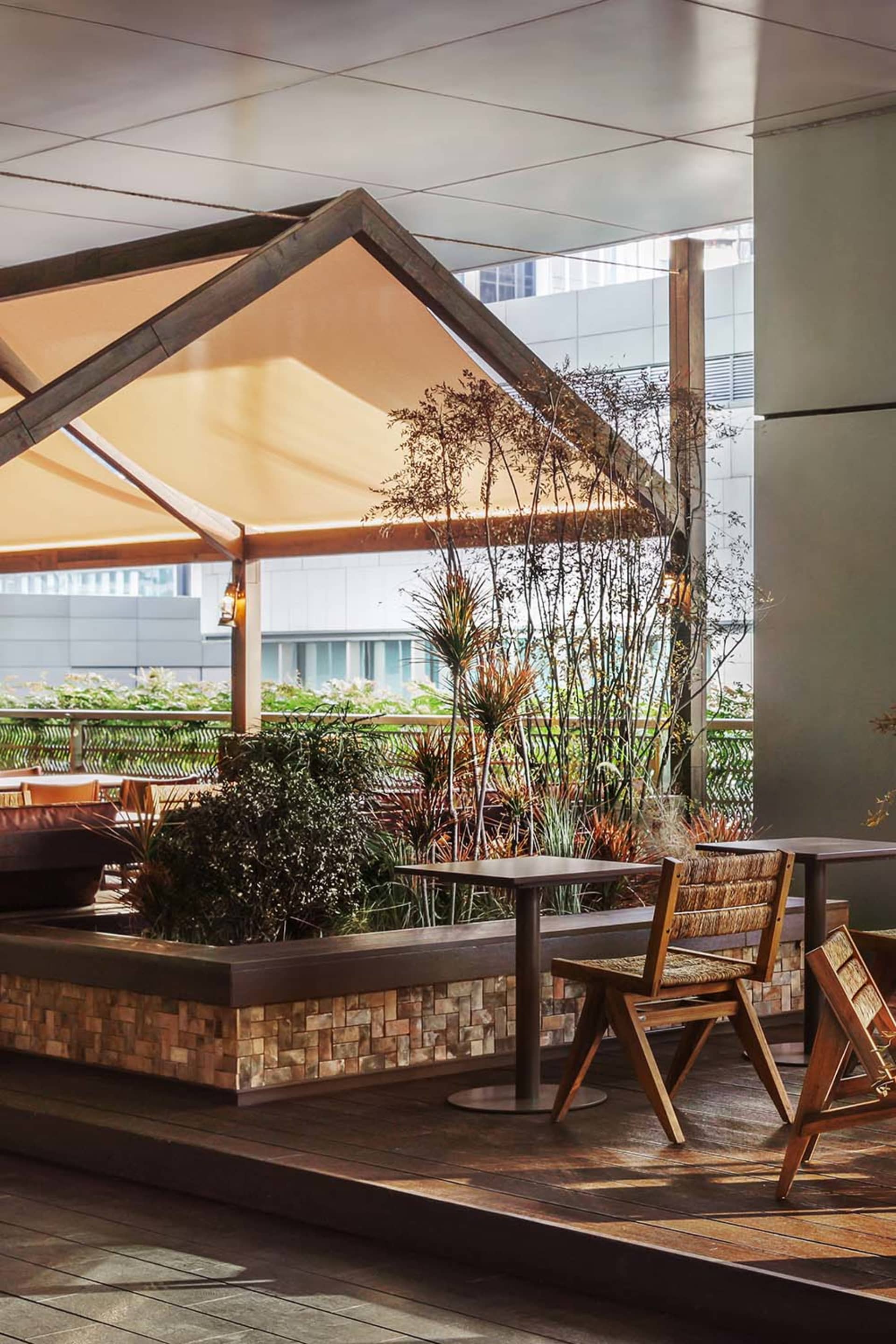 A dining area with a wooden table and chairs surrounded by potted plants and a vase, set in a restaurant or cafe with a relaxed atmosphere