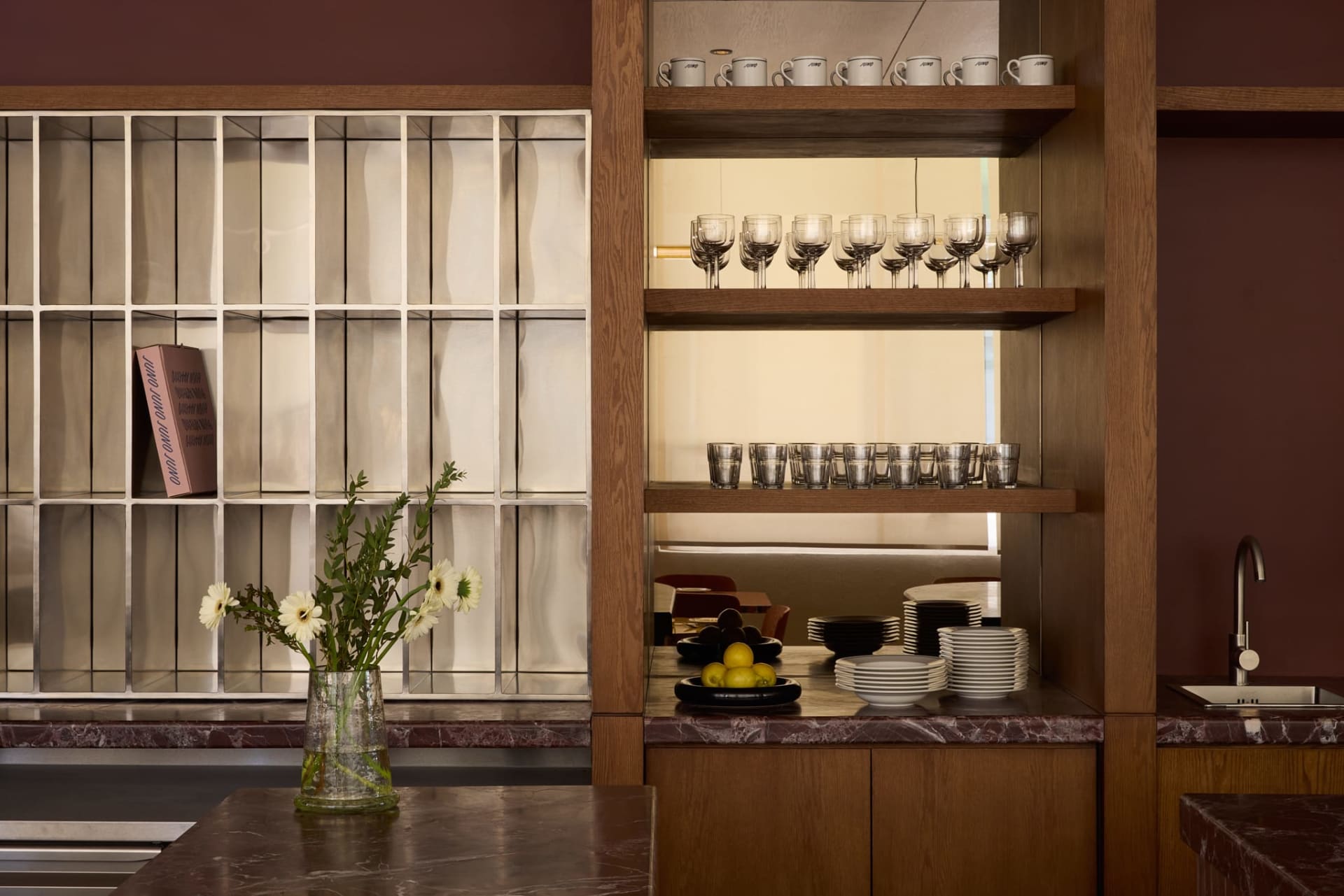 Modern kitchen with a marble countertop, wooden cabinet, and various decorative items on the countertop