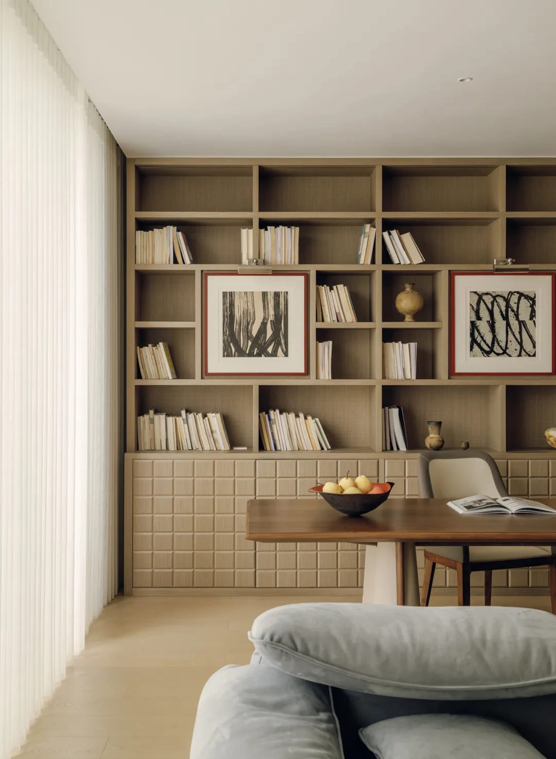 A well-lit living room with a wooden table and chairs, surrounded by books, creating a cozy and intellectual atmosphere