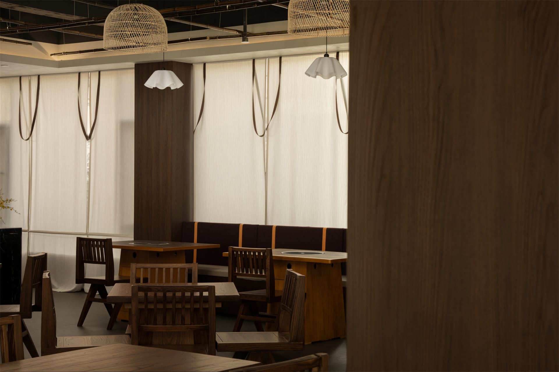 Cozy restaurant dining area with wooden tables and chairs, dim lighting, and a warm atmosphere