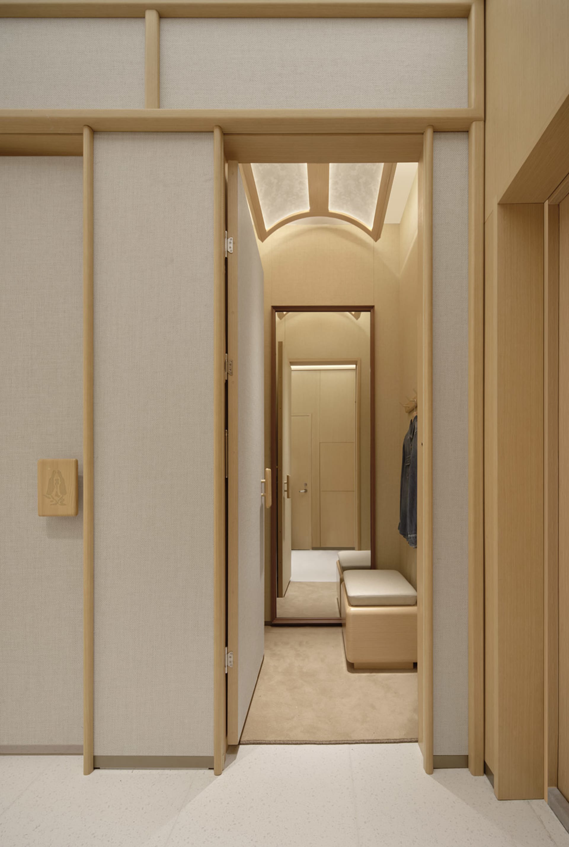 A modern bedroom with a wooden floor and brown carpet, featuring a bed and soft, diffused lighting