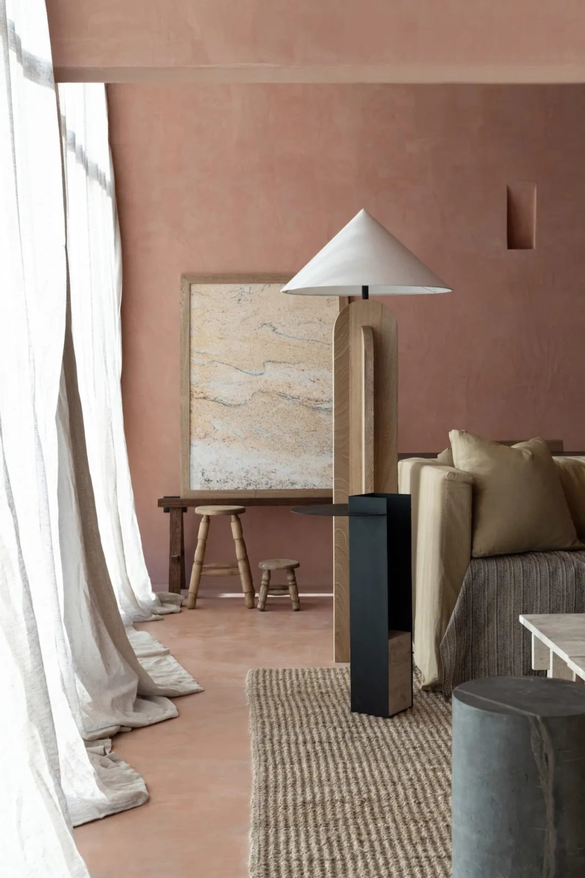 Cozy living room with a pink accent wall, a couch, a chair, and a lamp, set against a neutral background with a warm and inviting atmosphere