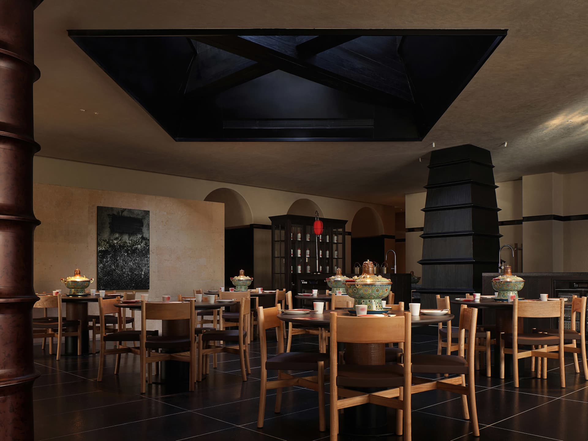 A modern restaurant with a large dining area featuring multiple tables and chairs, set with various items, and soft warm lighting creating a cozy atmosphere