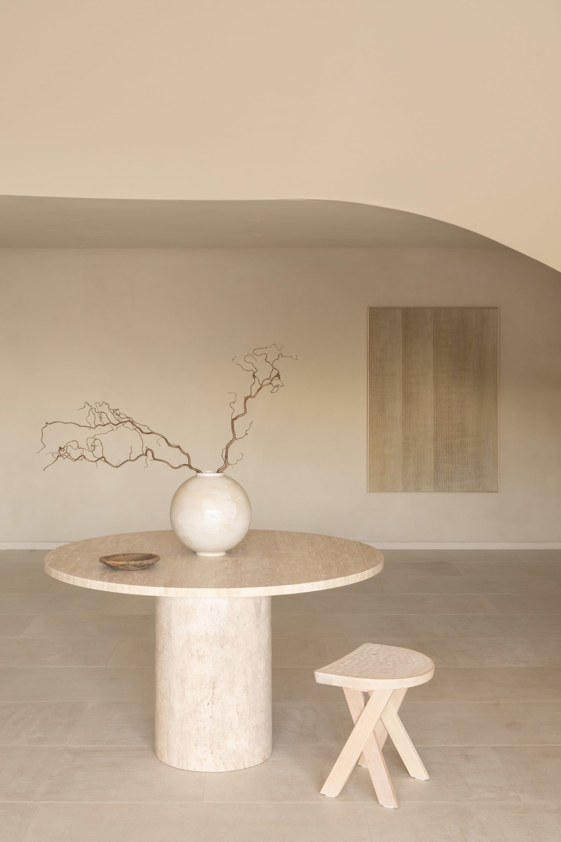 A minimalist dining area with a white table, a ceramic vase, and a couch and chair, surrounded by soft and diffused lighting