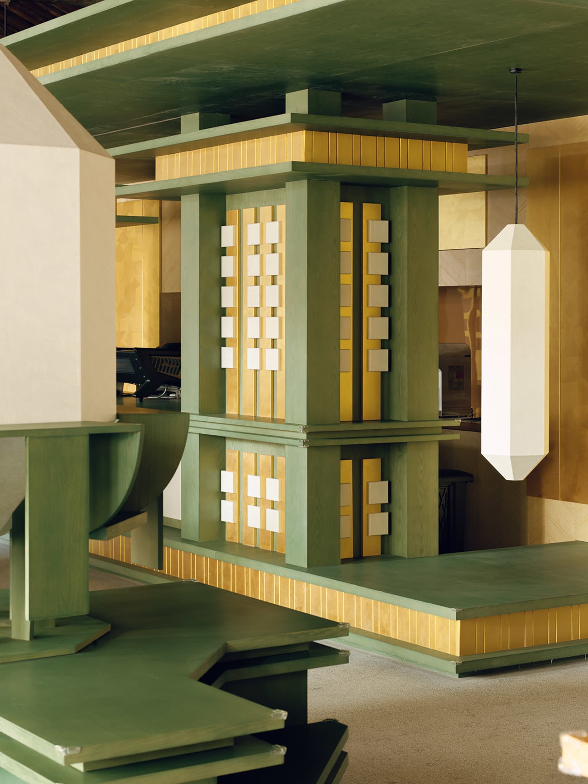 Cozy living space with a green and yellow color scheme, featuring a wooden structure, dining table, chairs, couch, and piano, with dim lighting creating a warm ambiance