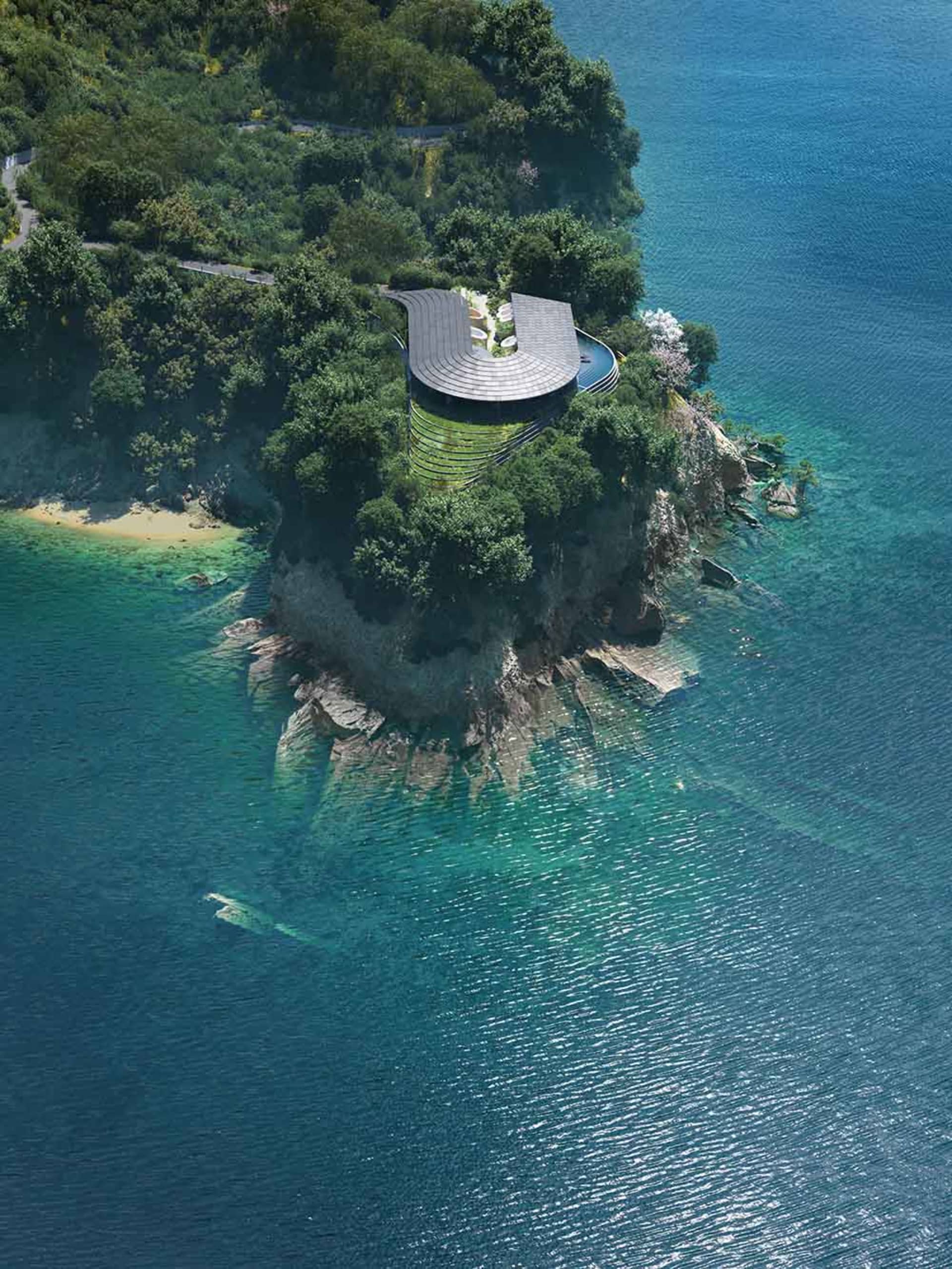 A serene coastal house with a stone exterior, surrounded by lush greenery and overlooking the ocean