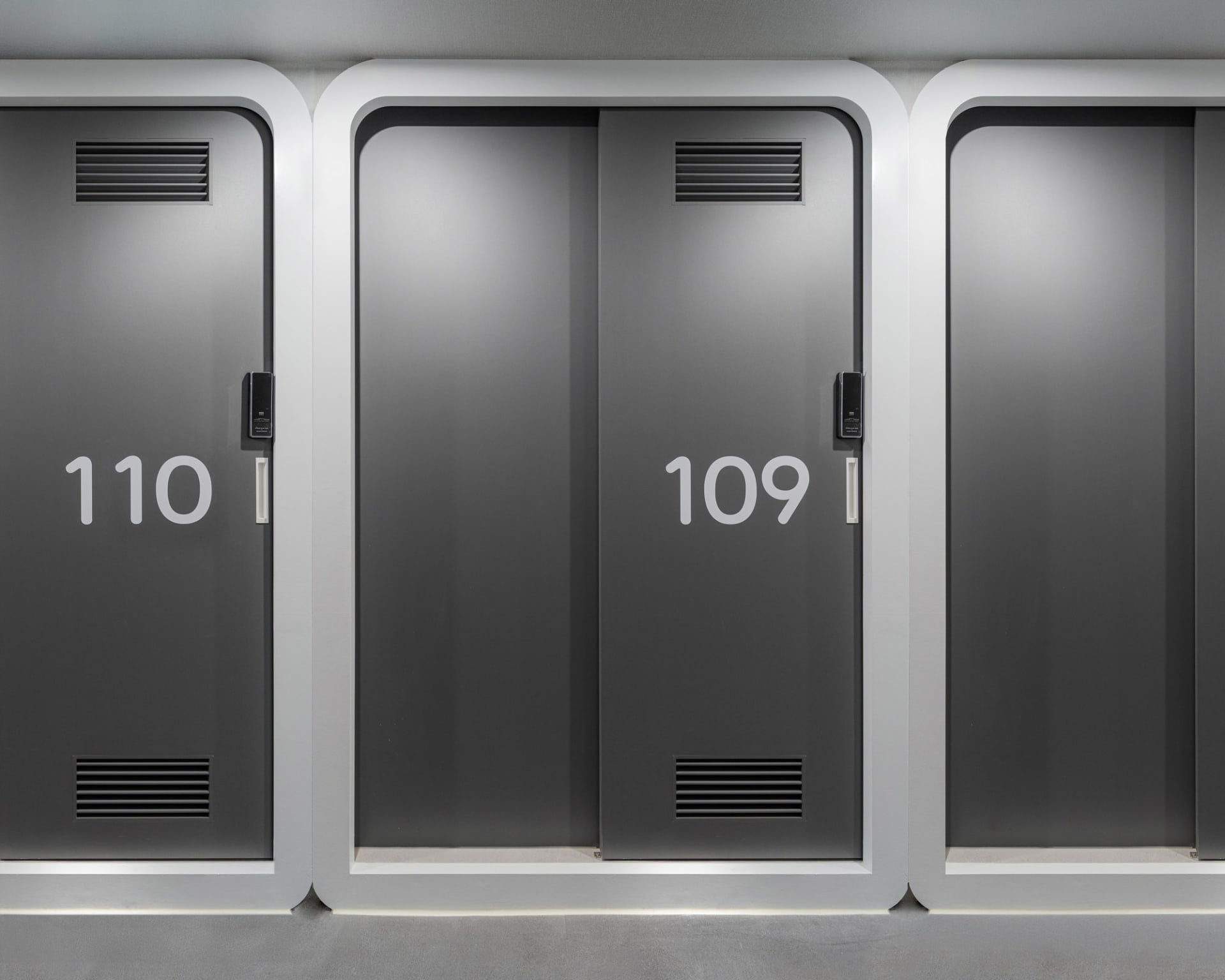 A dimly lit hallway with two black doors, each labeled with the number 109, in a grayish room