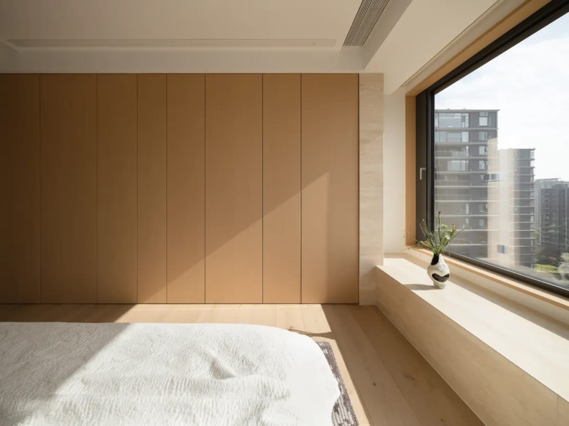 A calm and relaxing bedroom with a wooden floor, a bed, and a window, well-lit for a bright atmosphere