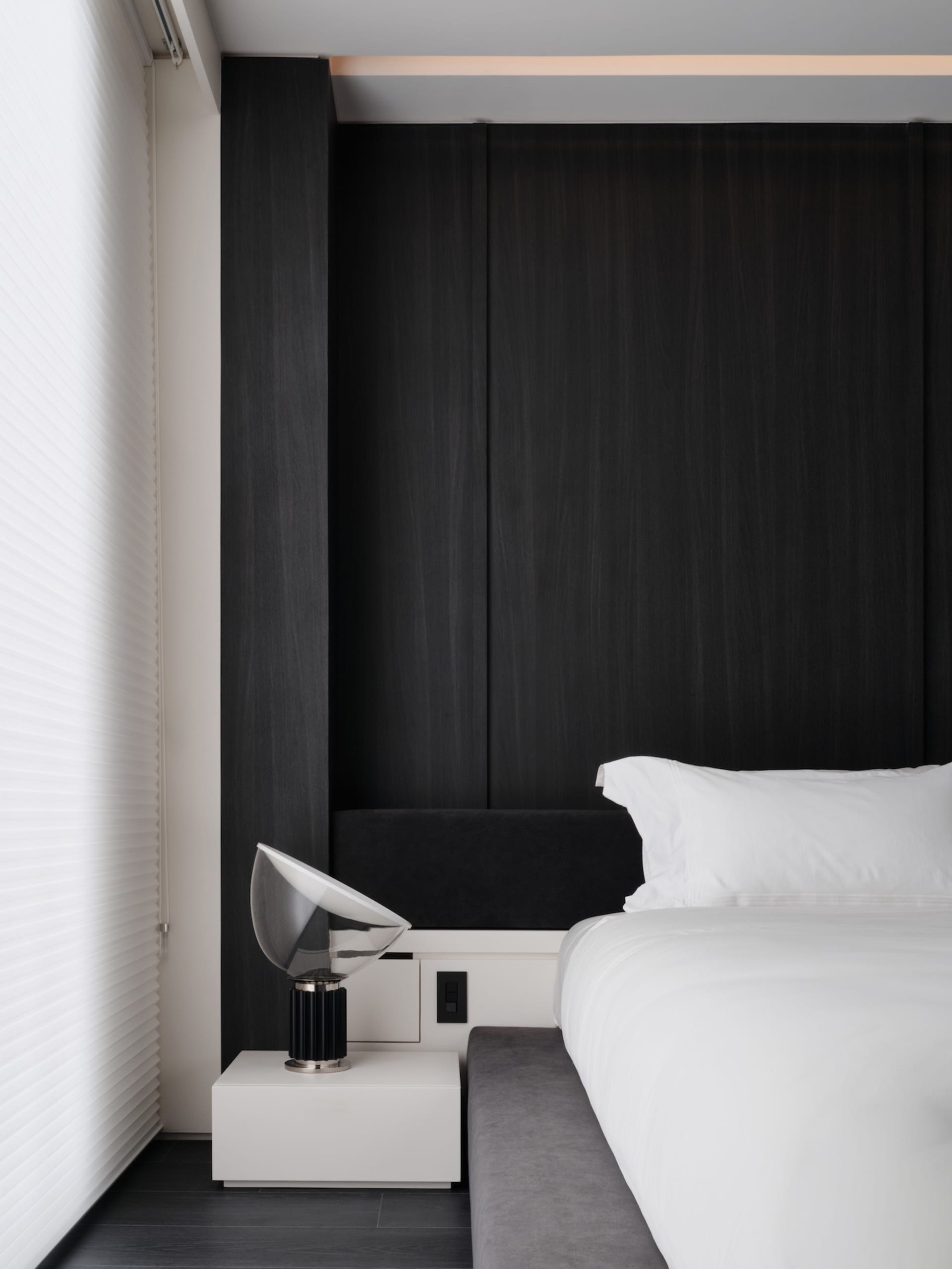 Cozy bedroom with a black bed frame, white comforter, and natural light from a window with white curtains