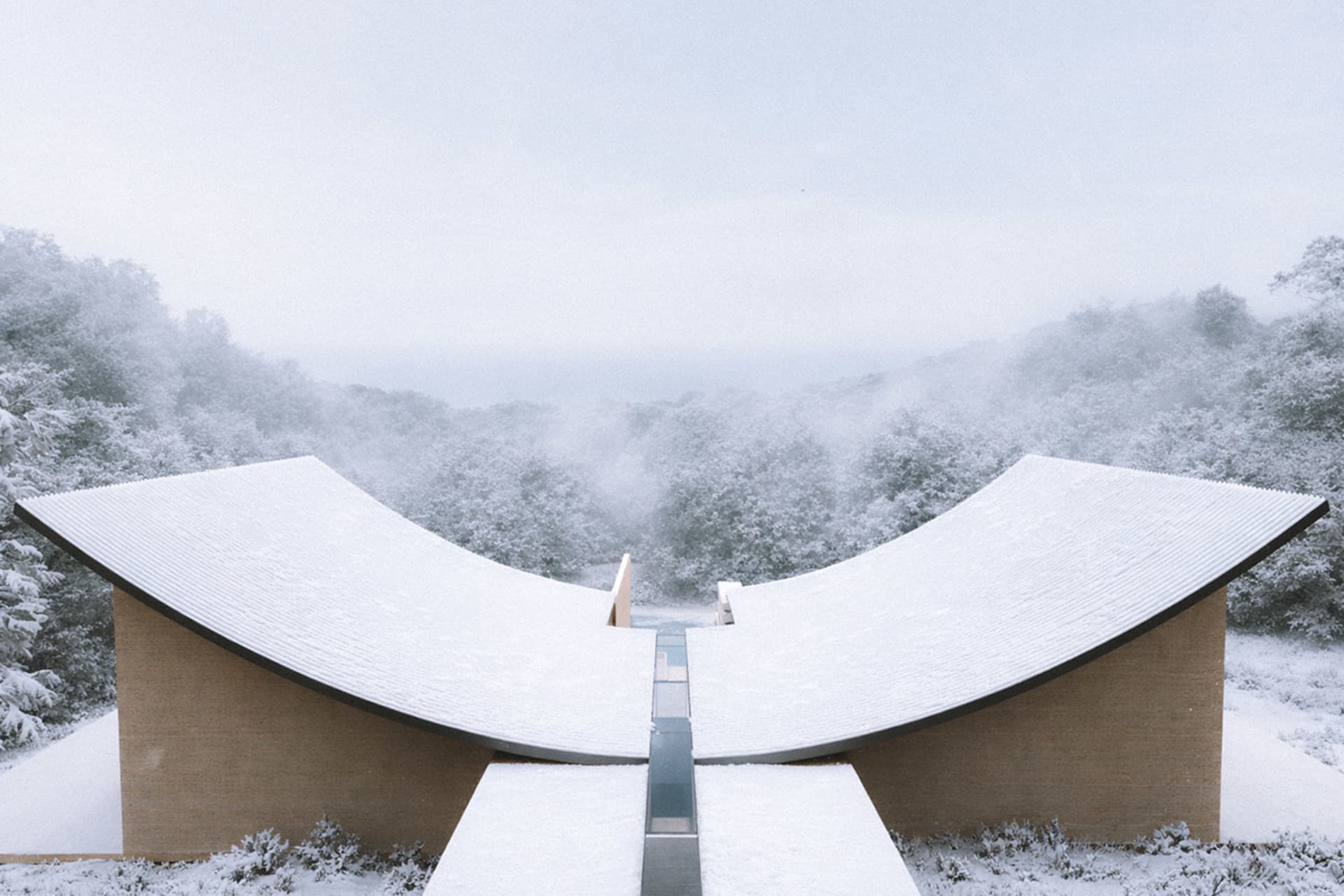 一座曲線的現代建築被置於一片寧靜的雪覆蓋的景色中